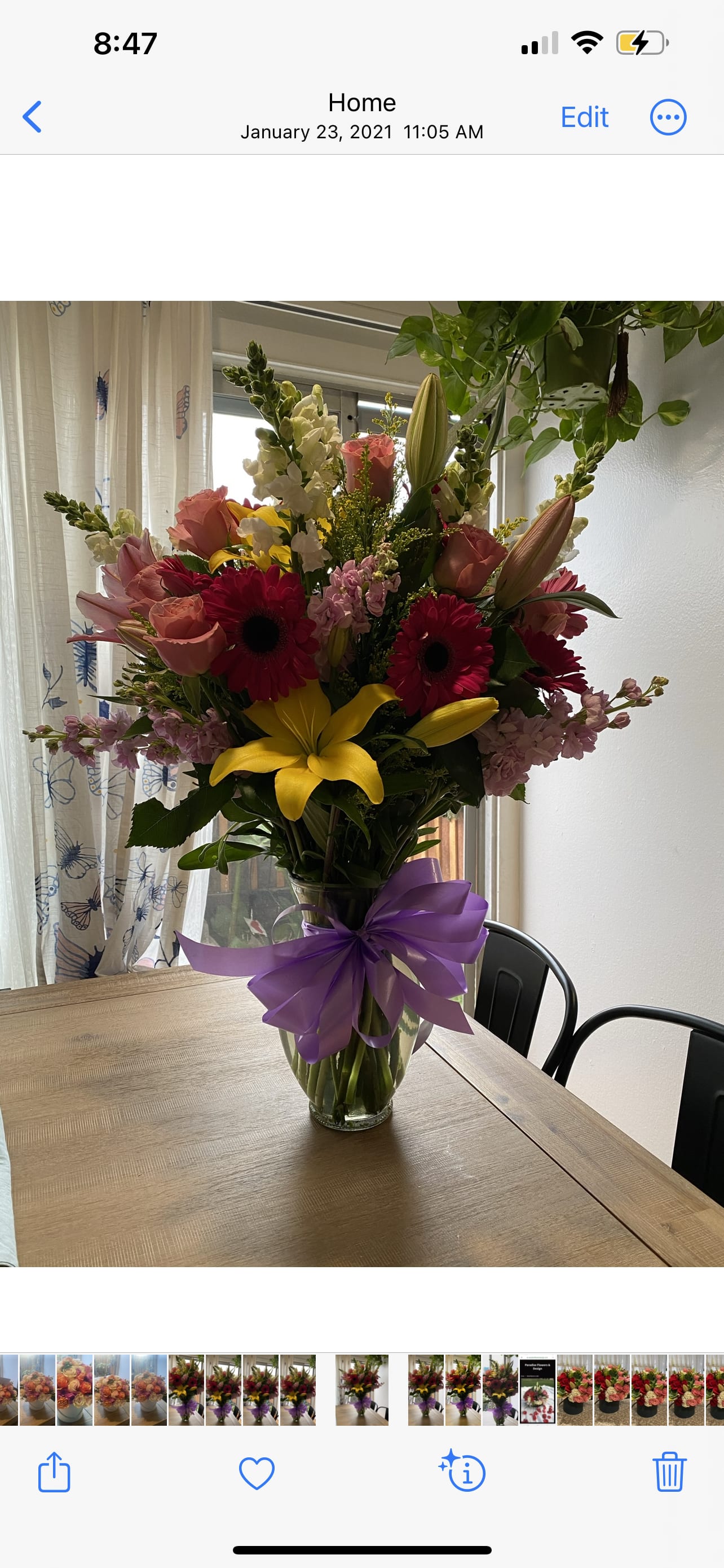 Mixed bouquet of pink, yellow, and white flowers in a glass vase with a purple bow