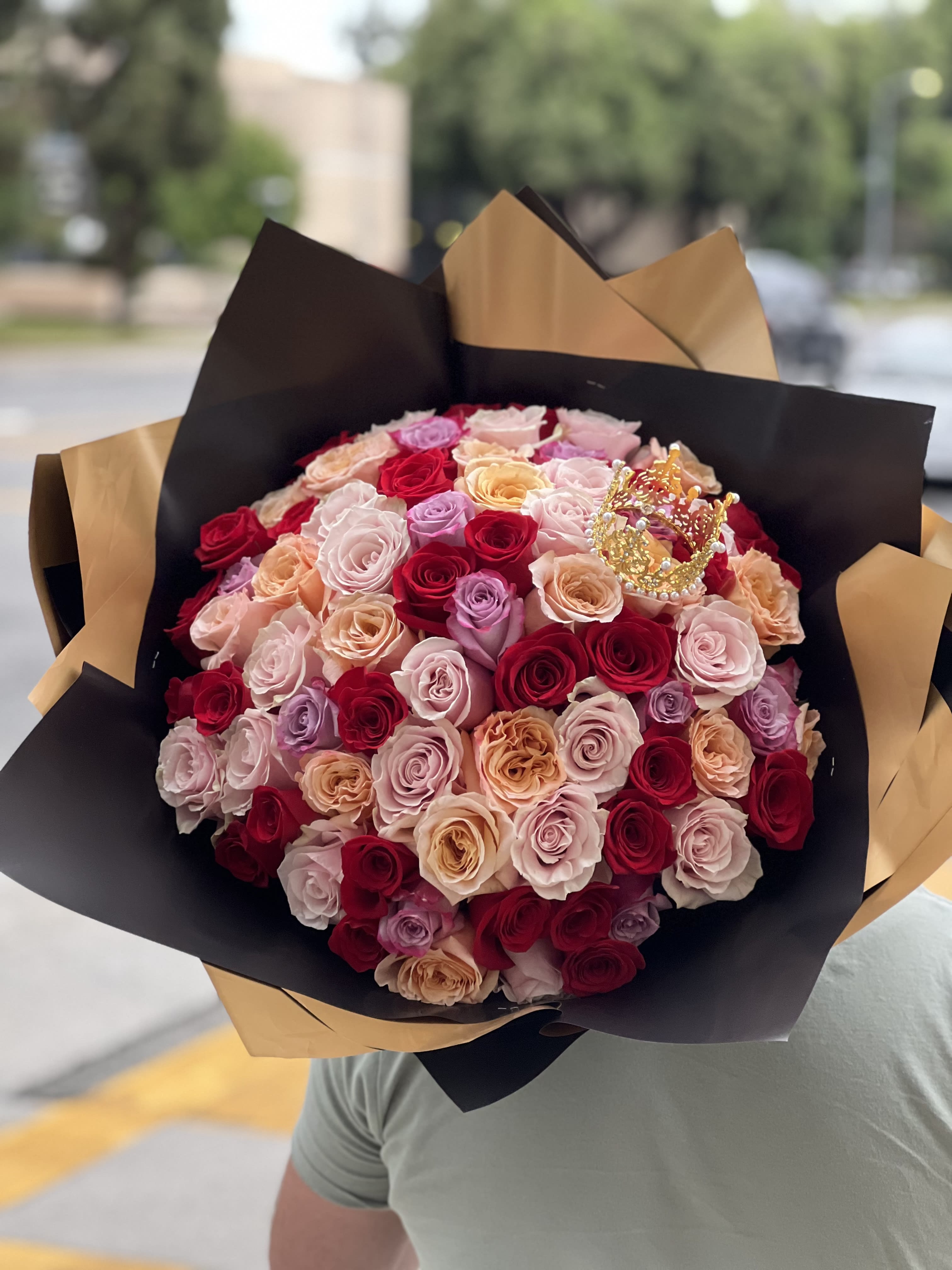 Large bouquet of multicolored roses wrapped in black and gold paper