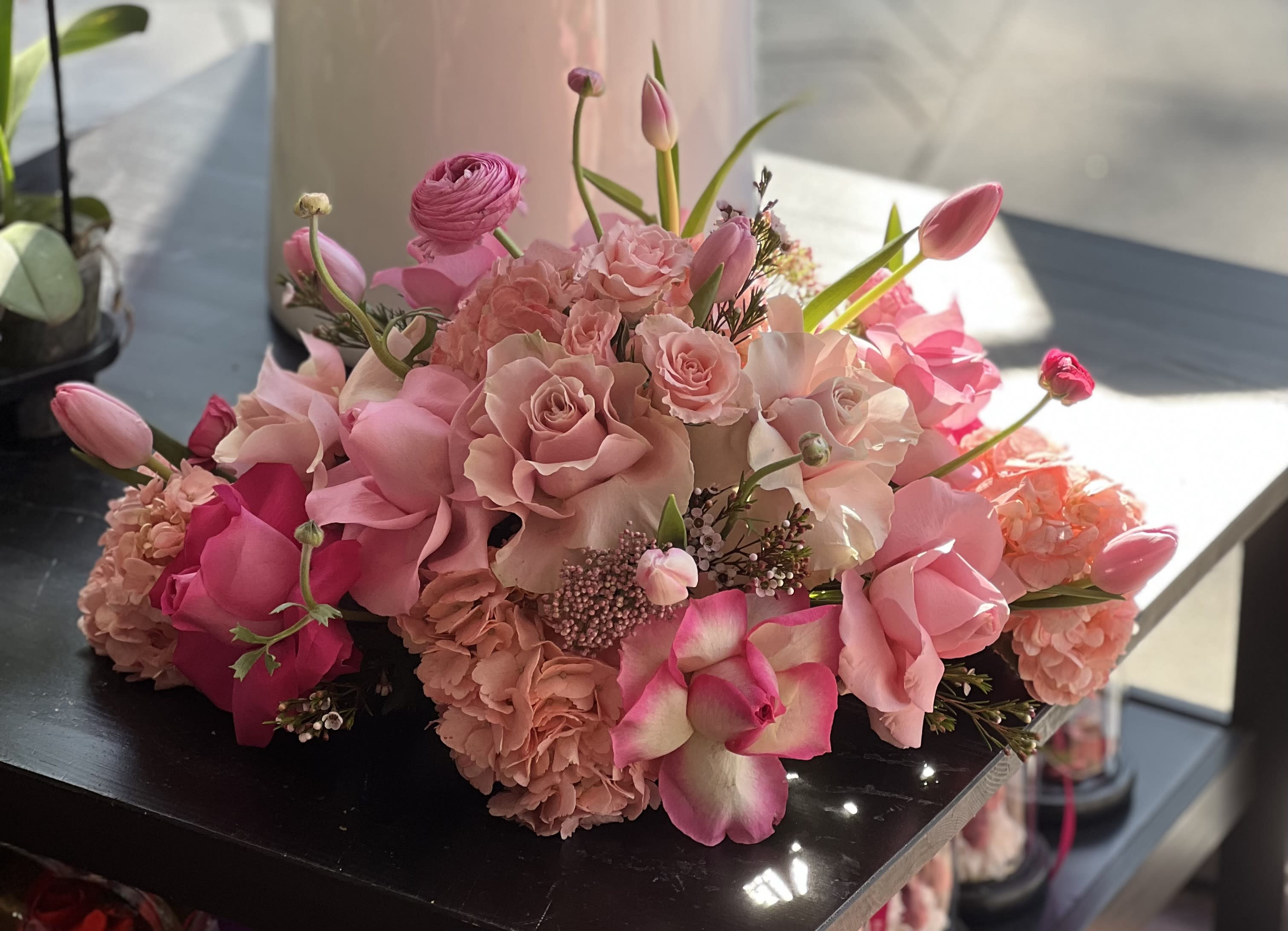 Pink bouquet with roses, tulips, and orchids arranged low and full