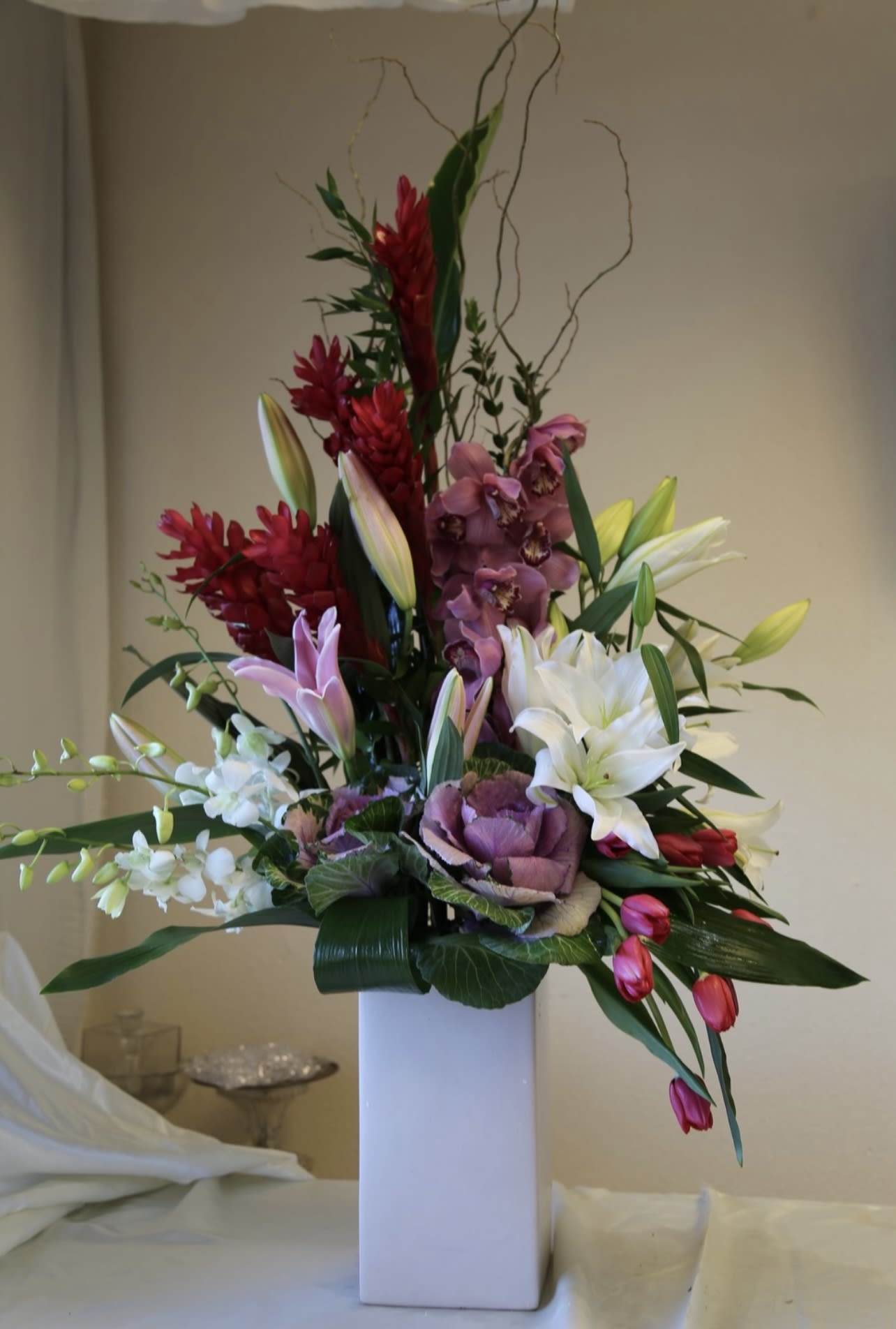 Tall mixed floral arrangement in a white rectangular vase