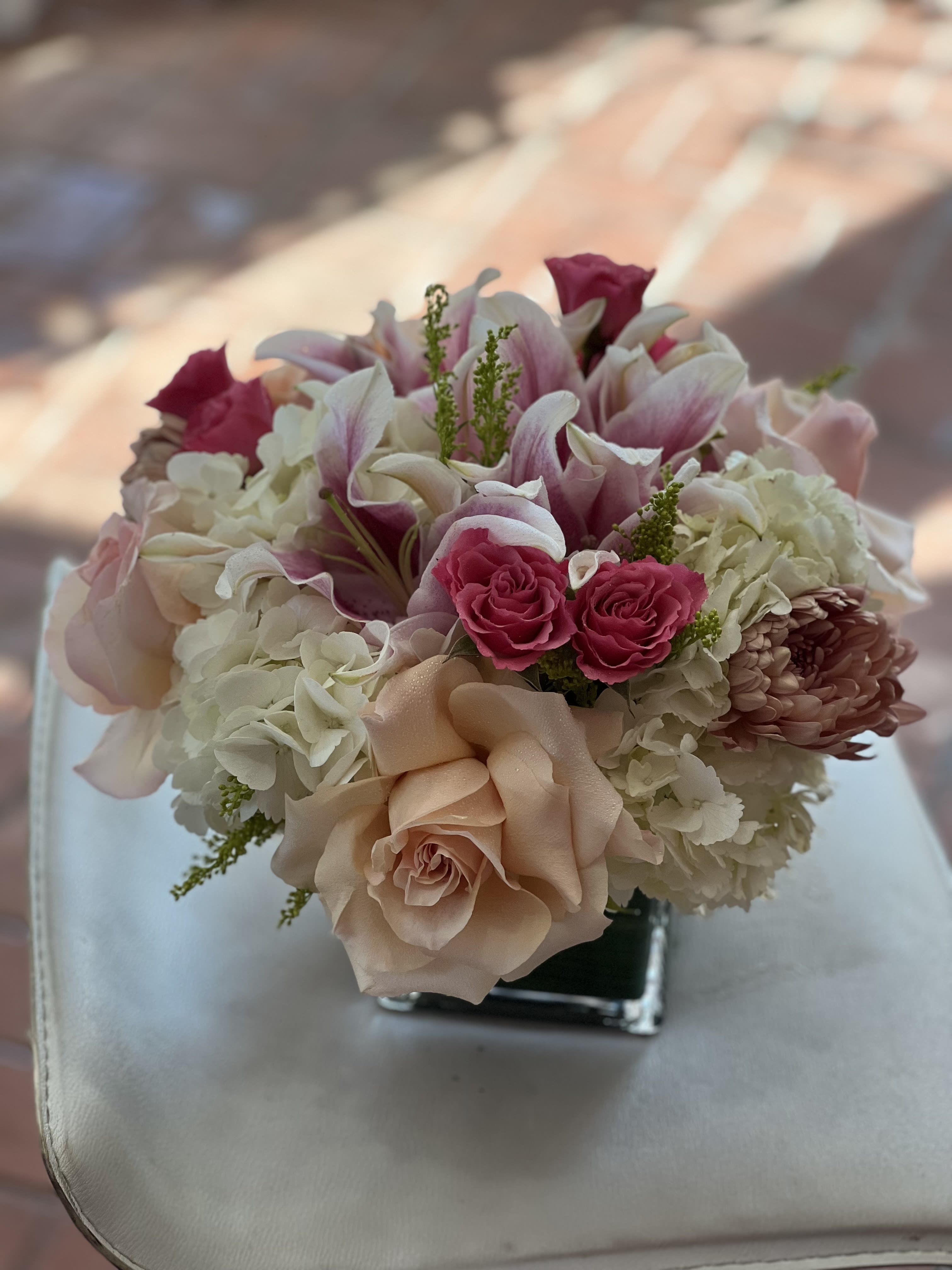 Pink and white bouquet with roses, lilies, and hydrangeas in a square vase