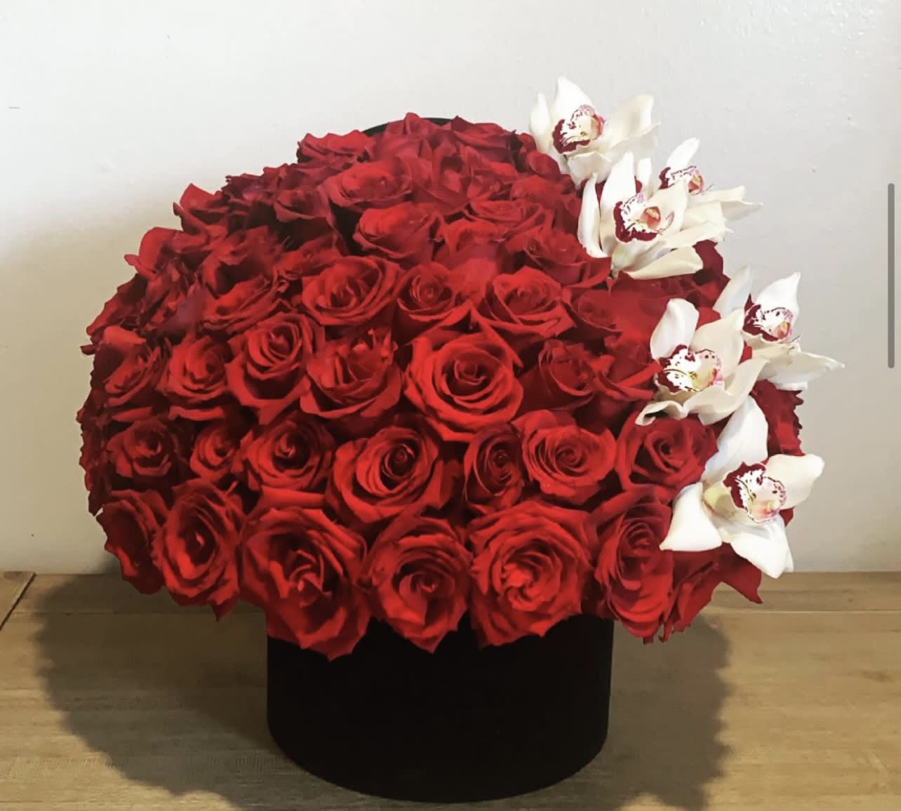 Large red rose arrangement with white orchids in a black box