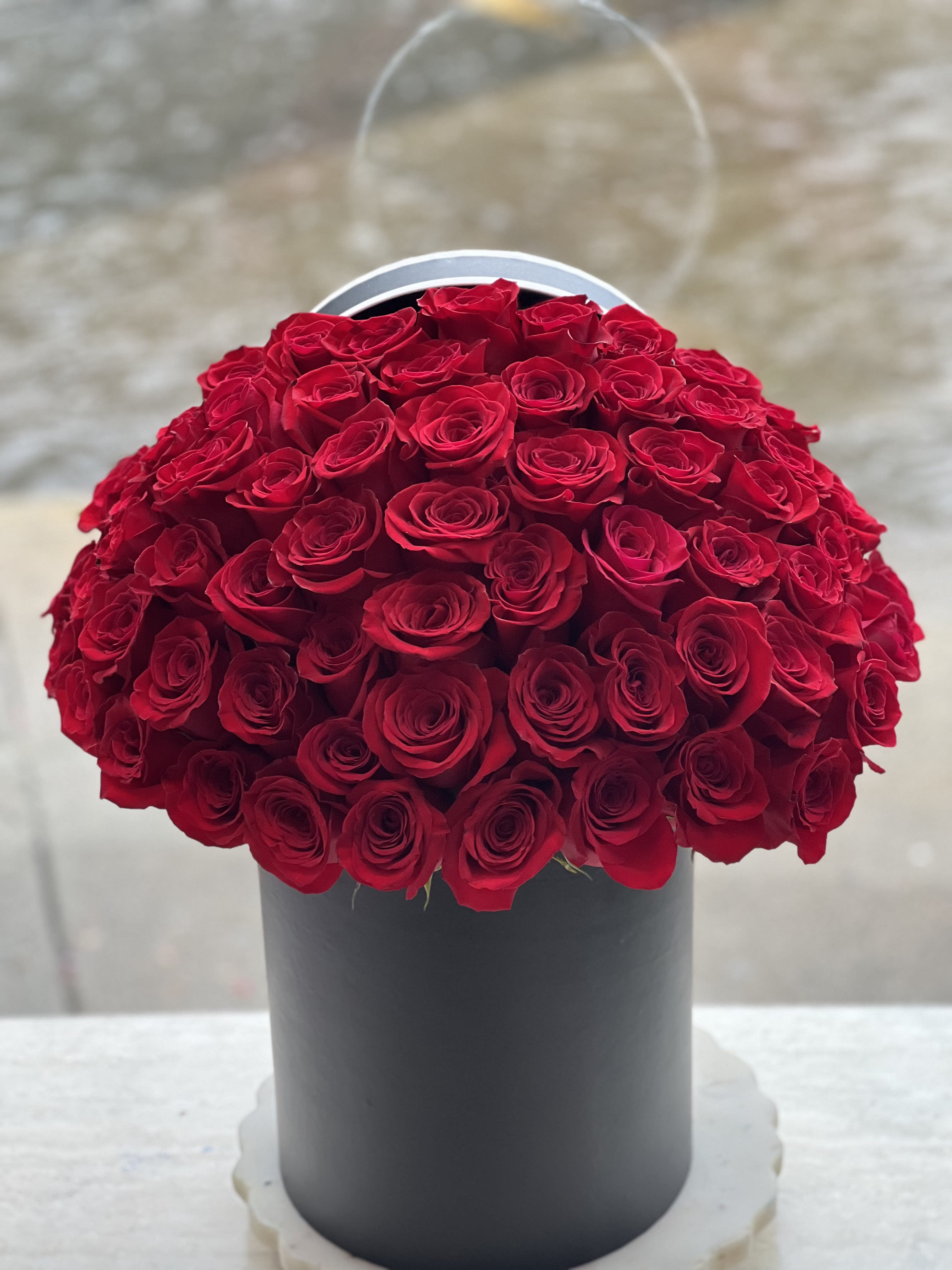 Large bouquet of red roses in a black hatbox