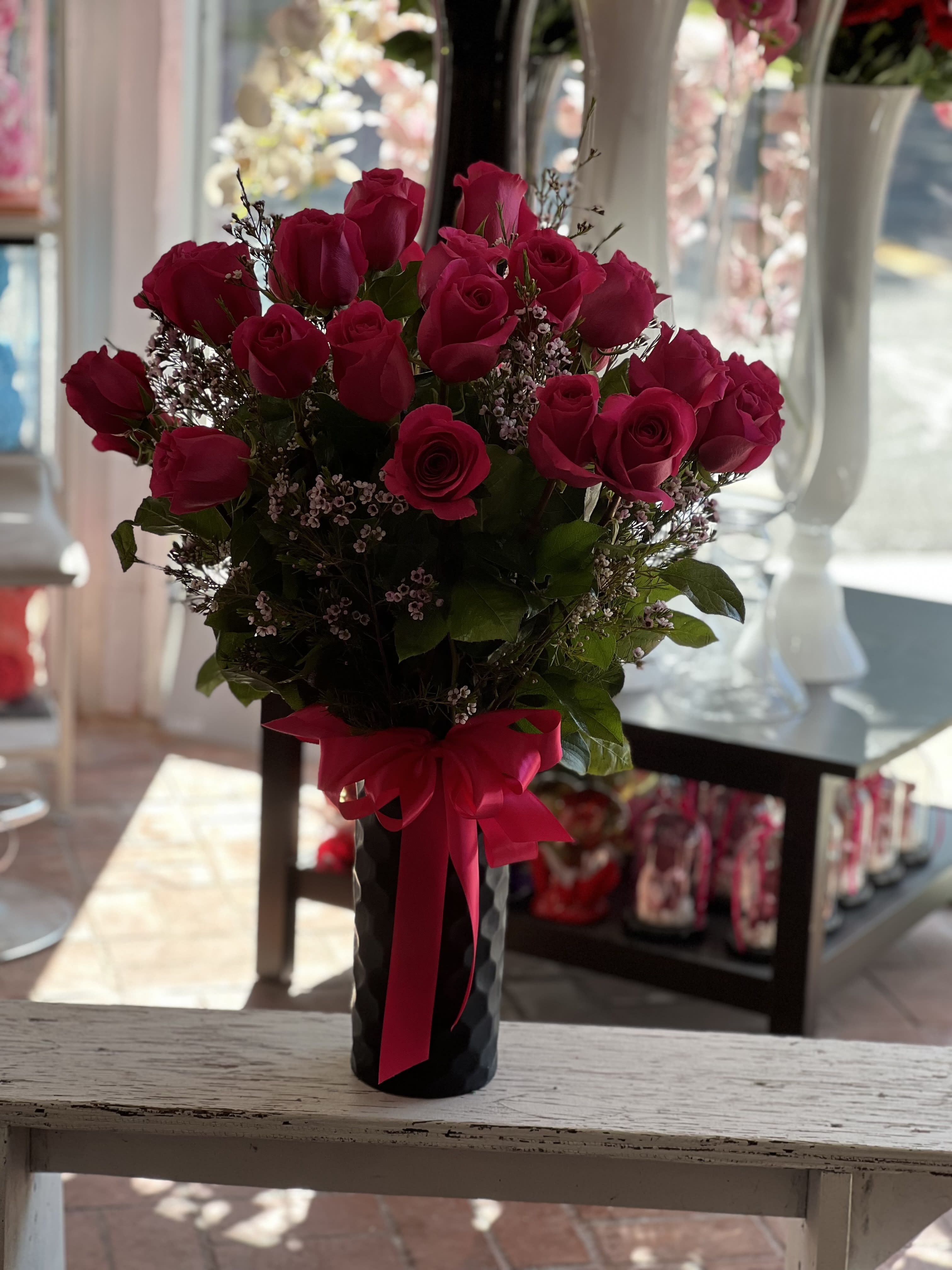 Bouquet of hot pink roses in a black vase with a pink ribbon