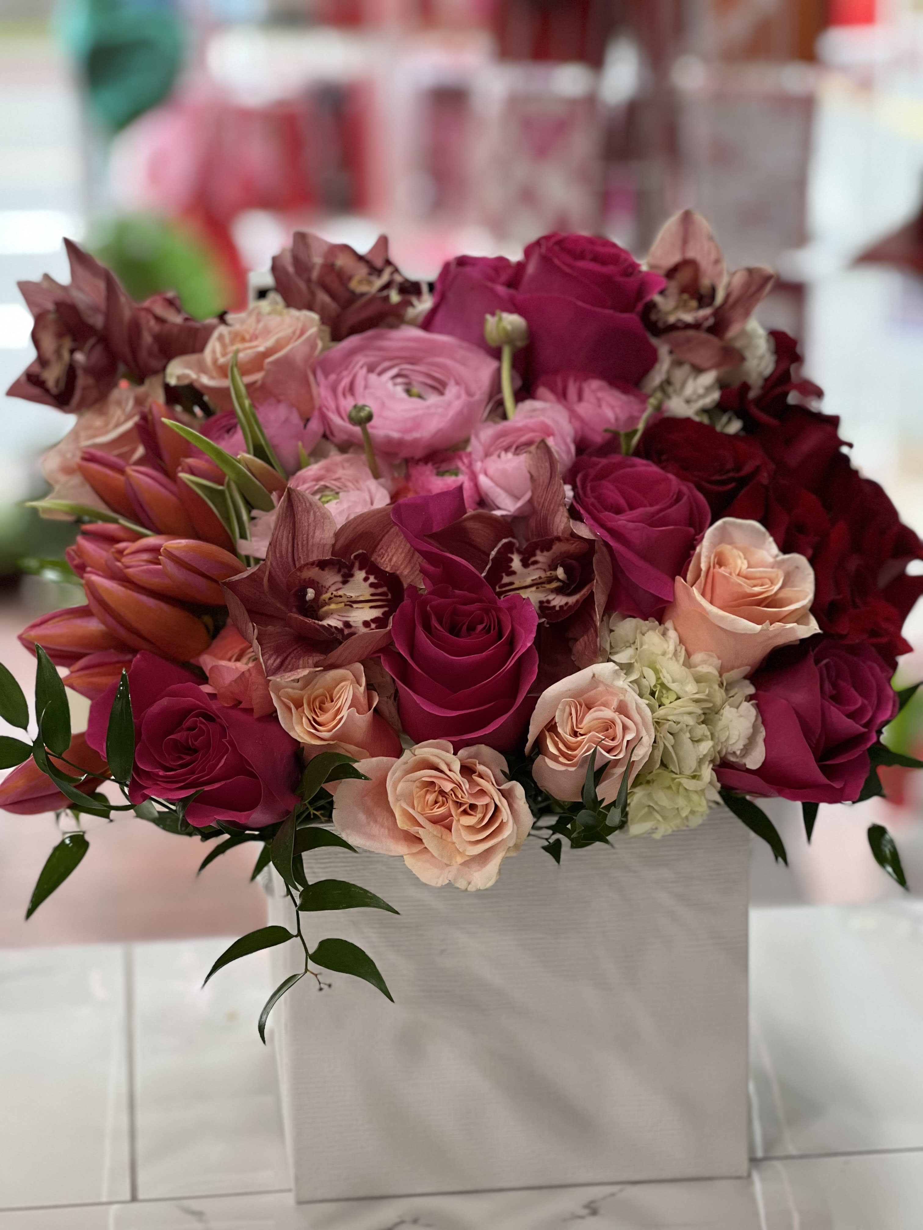 Pink and magenta roses with orchids in a white box