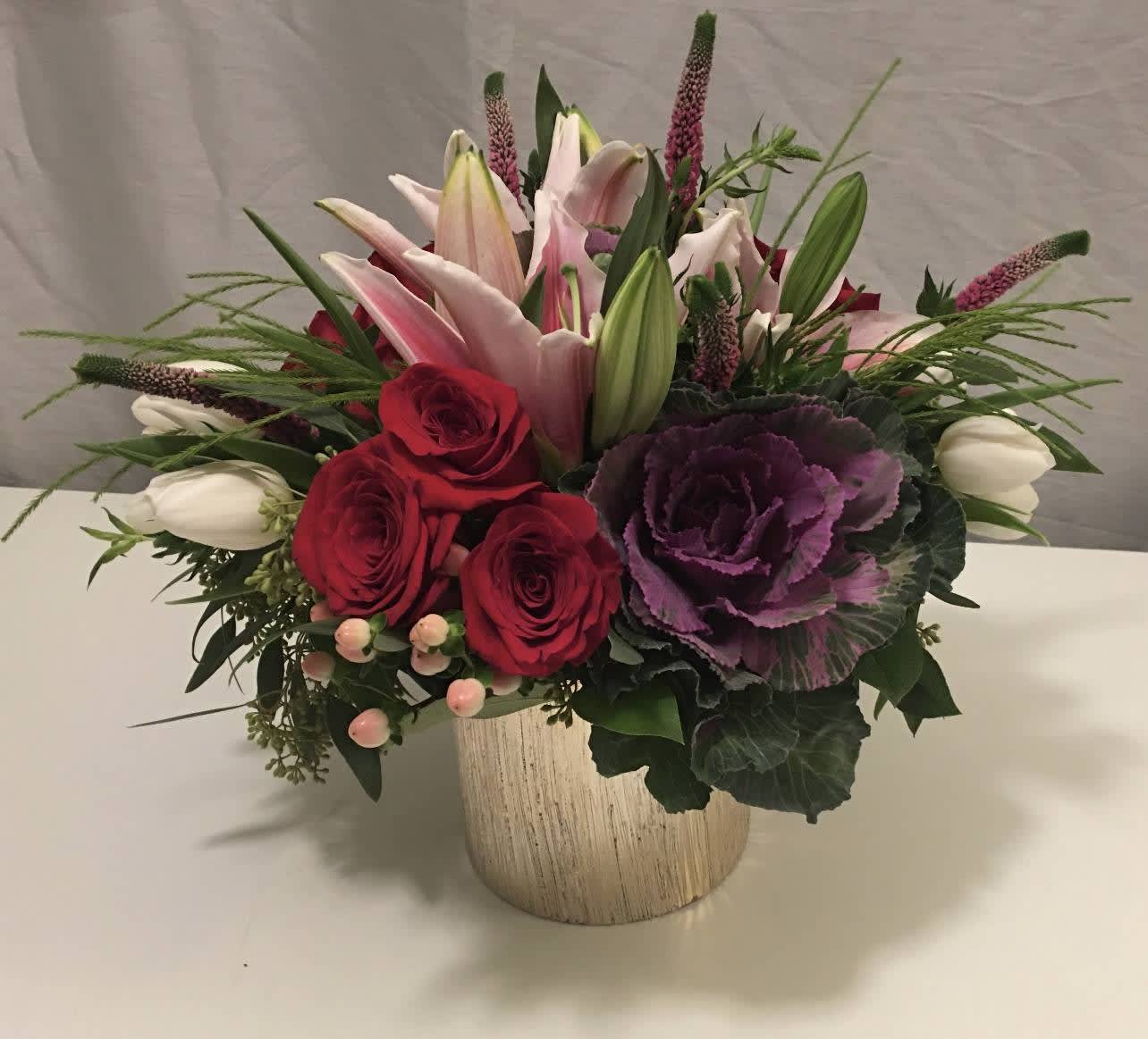 Mixed bouquet of red roses, pink lilies, and purple ornamental cabbage in a vase