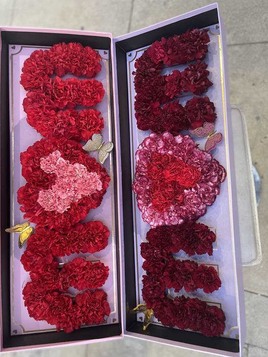Two open gift boxes filled with red and pink carnation letters