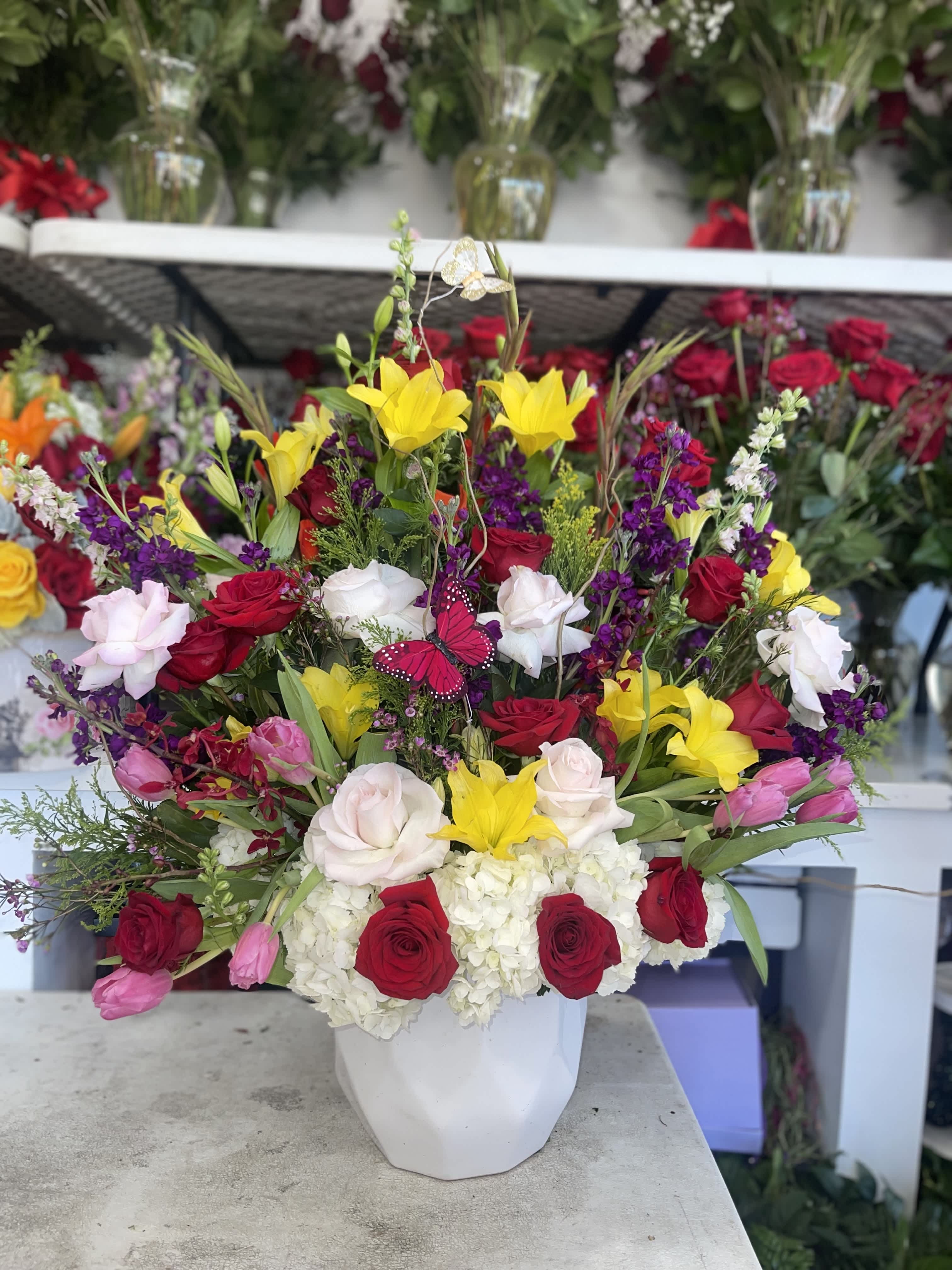 Mixed bouquet of roses, lilies, and hydrangeas in a white vase