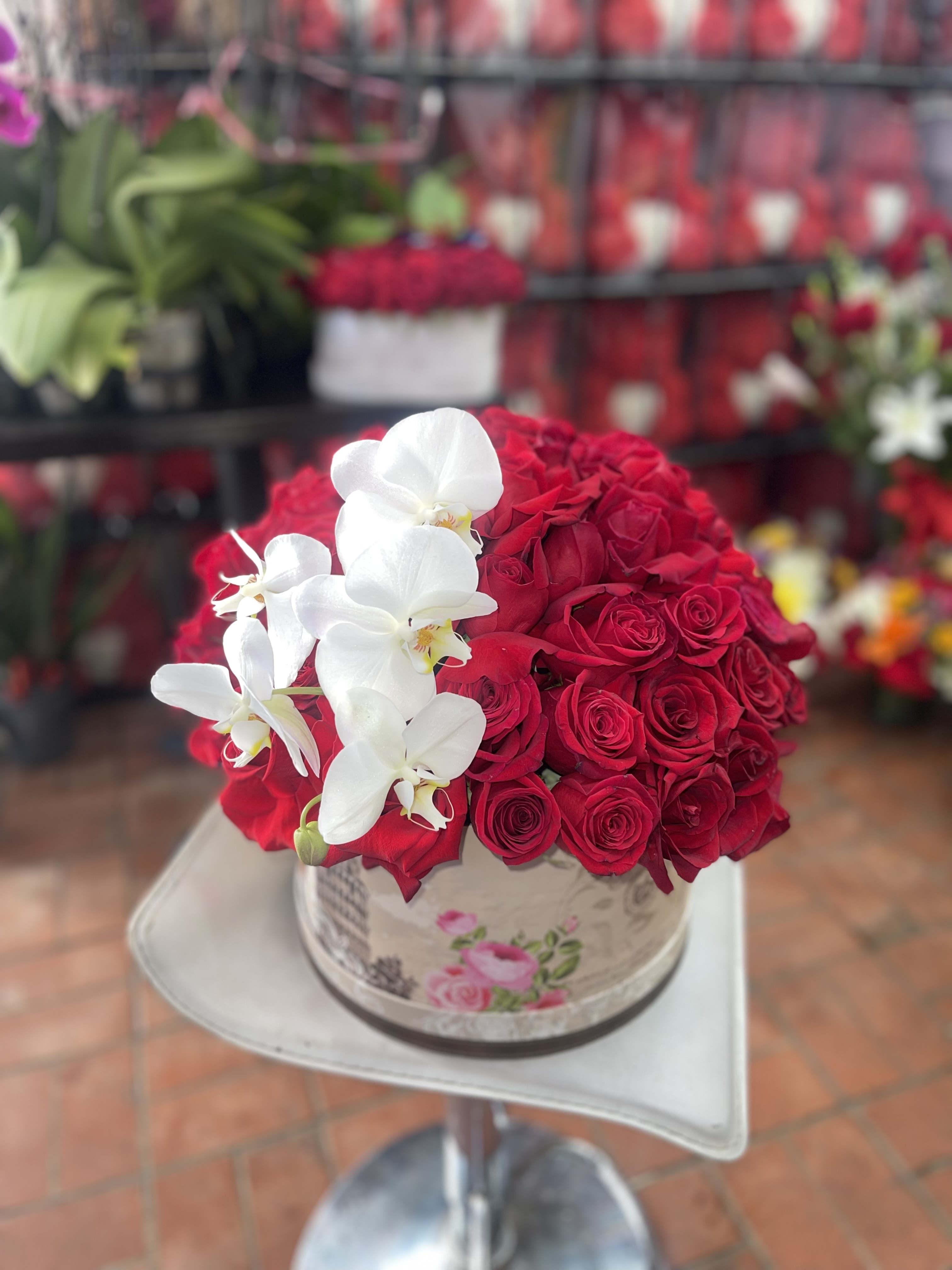 Red rose arrangement with white orchids in a round box