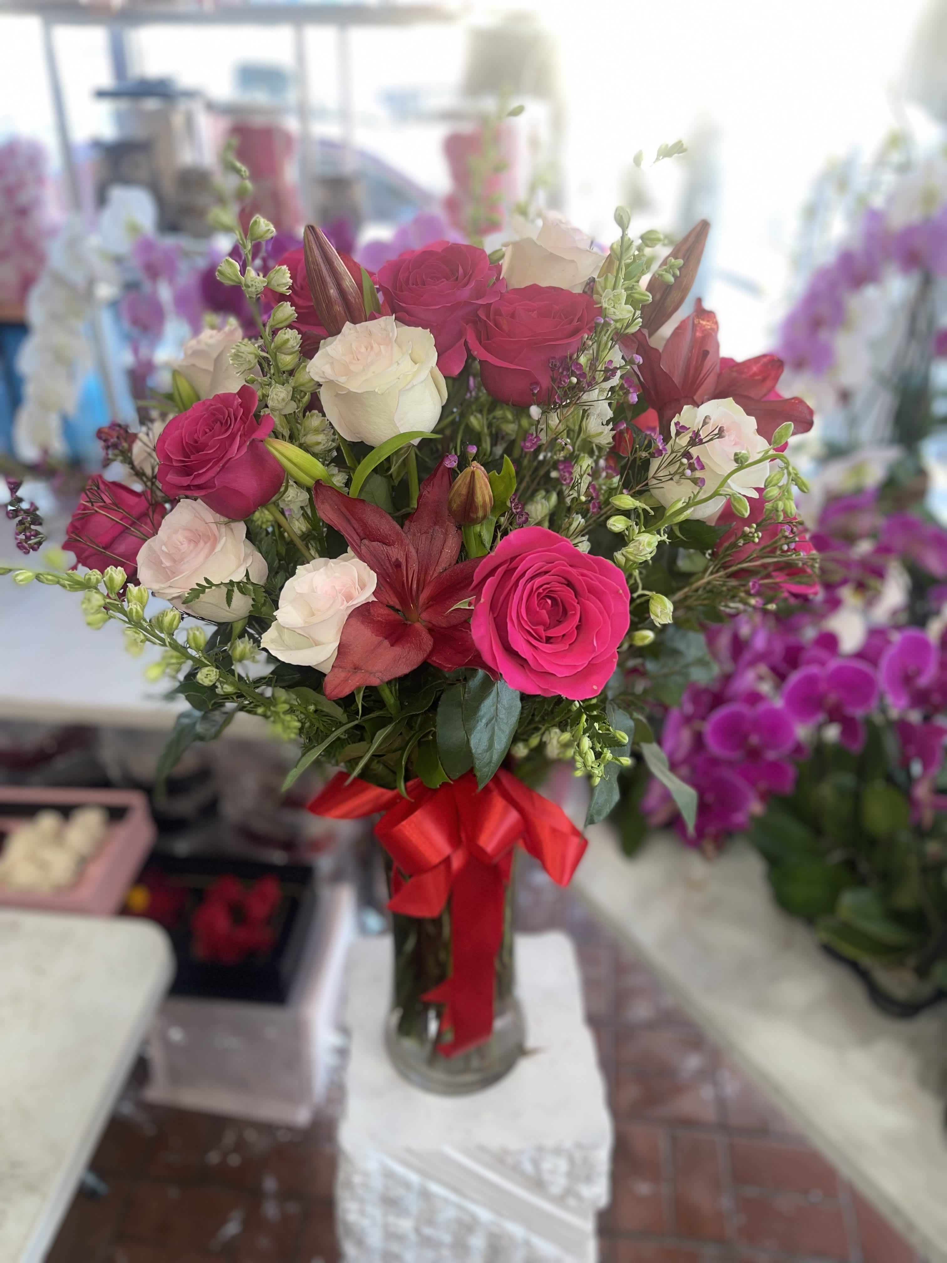 Bouquet of pink and white roses with red lilies in a glass vase