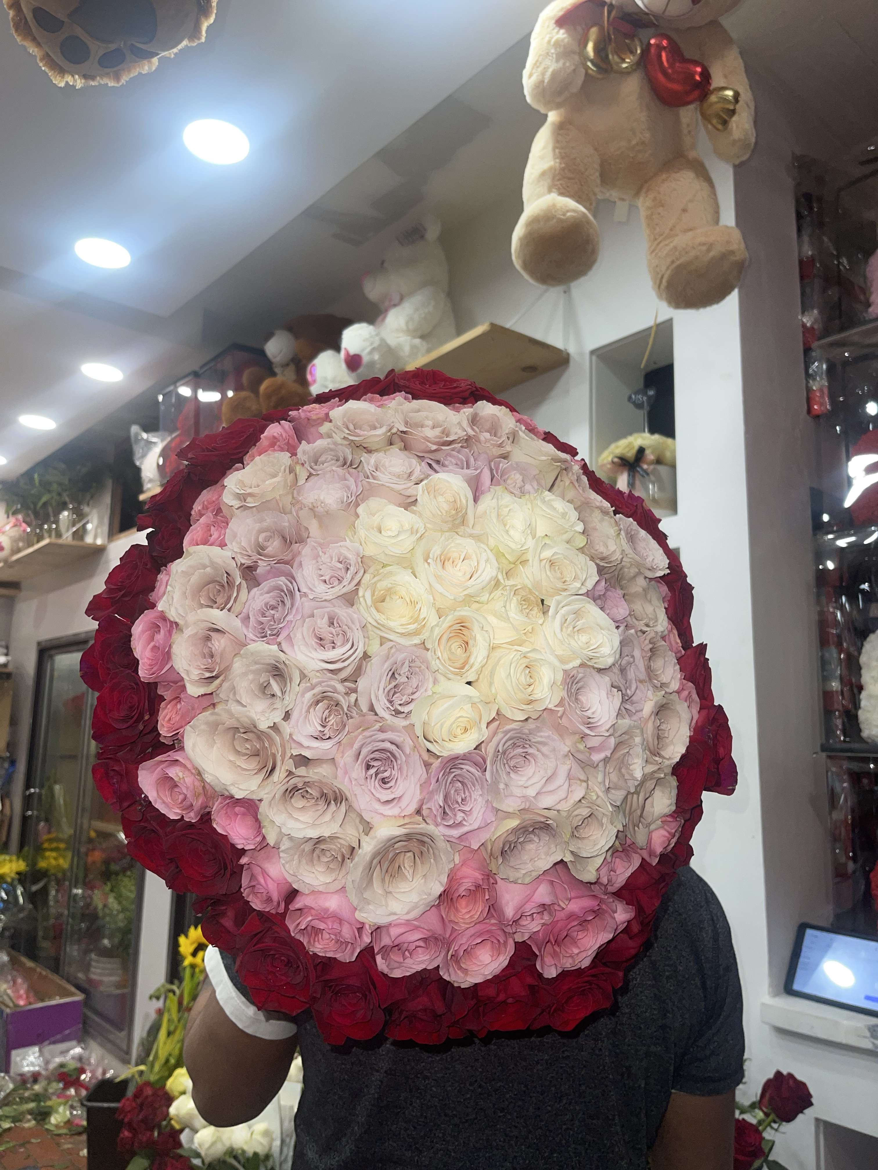 Large round bouquet of pink, cream, and red roses