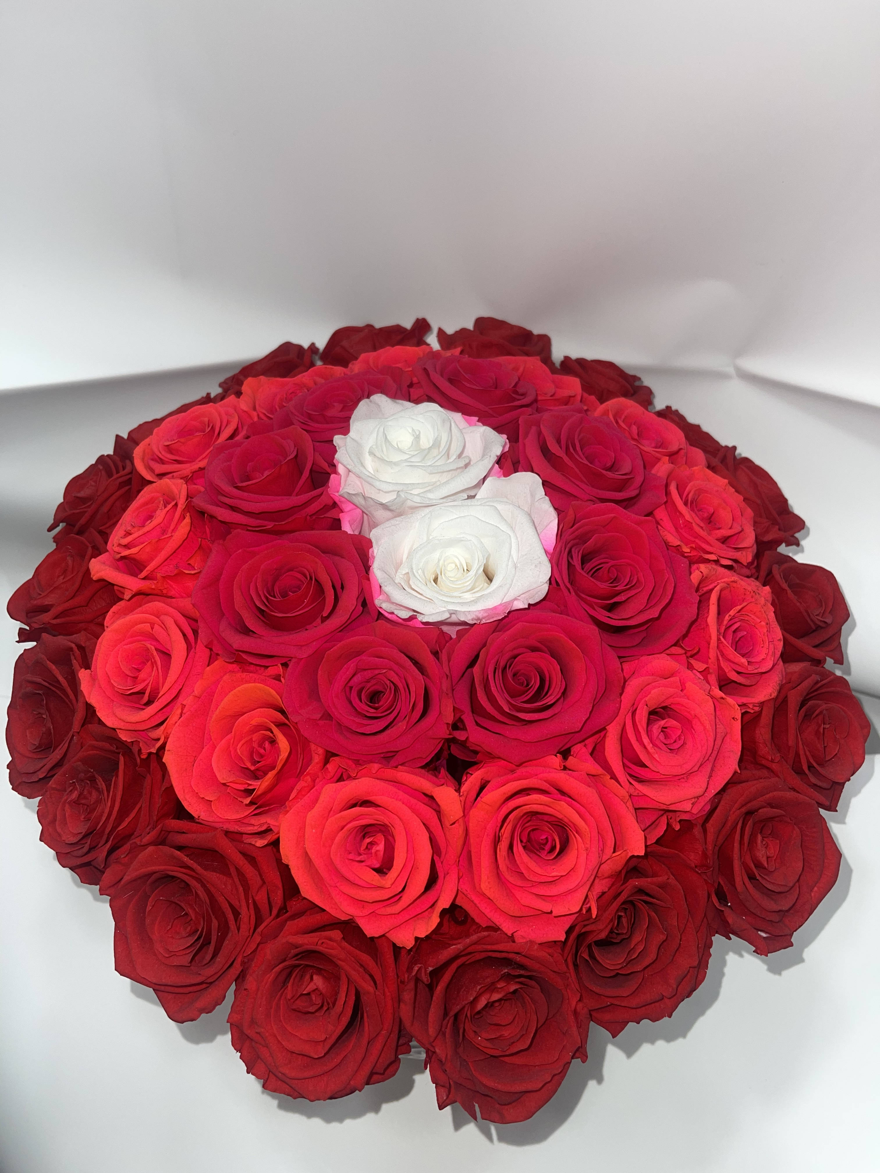 Round bouquet of red and white roses in a white box
