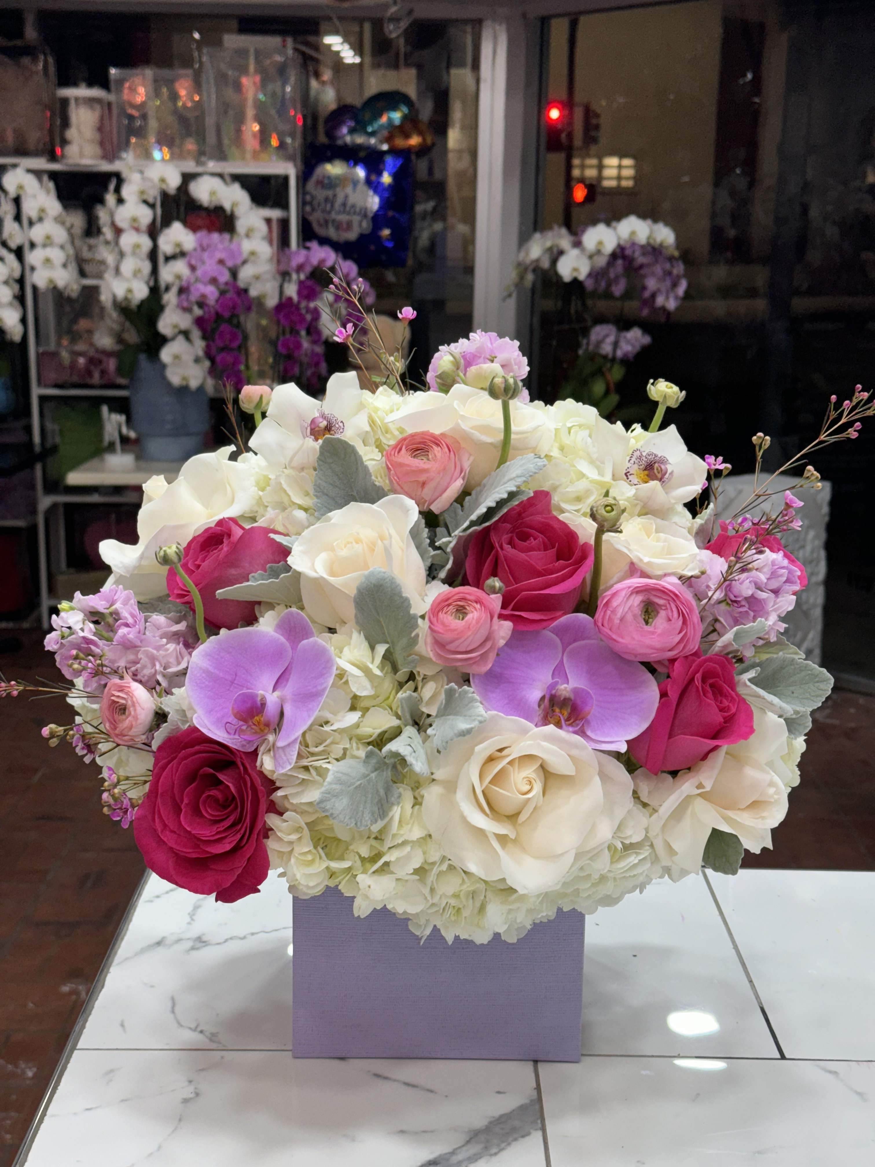 Bouquet of pink and white roses with orchids in a lavender box