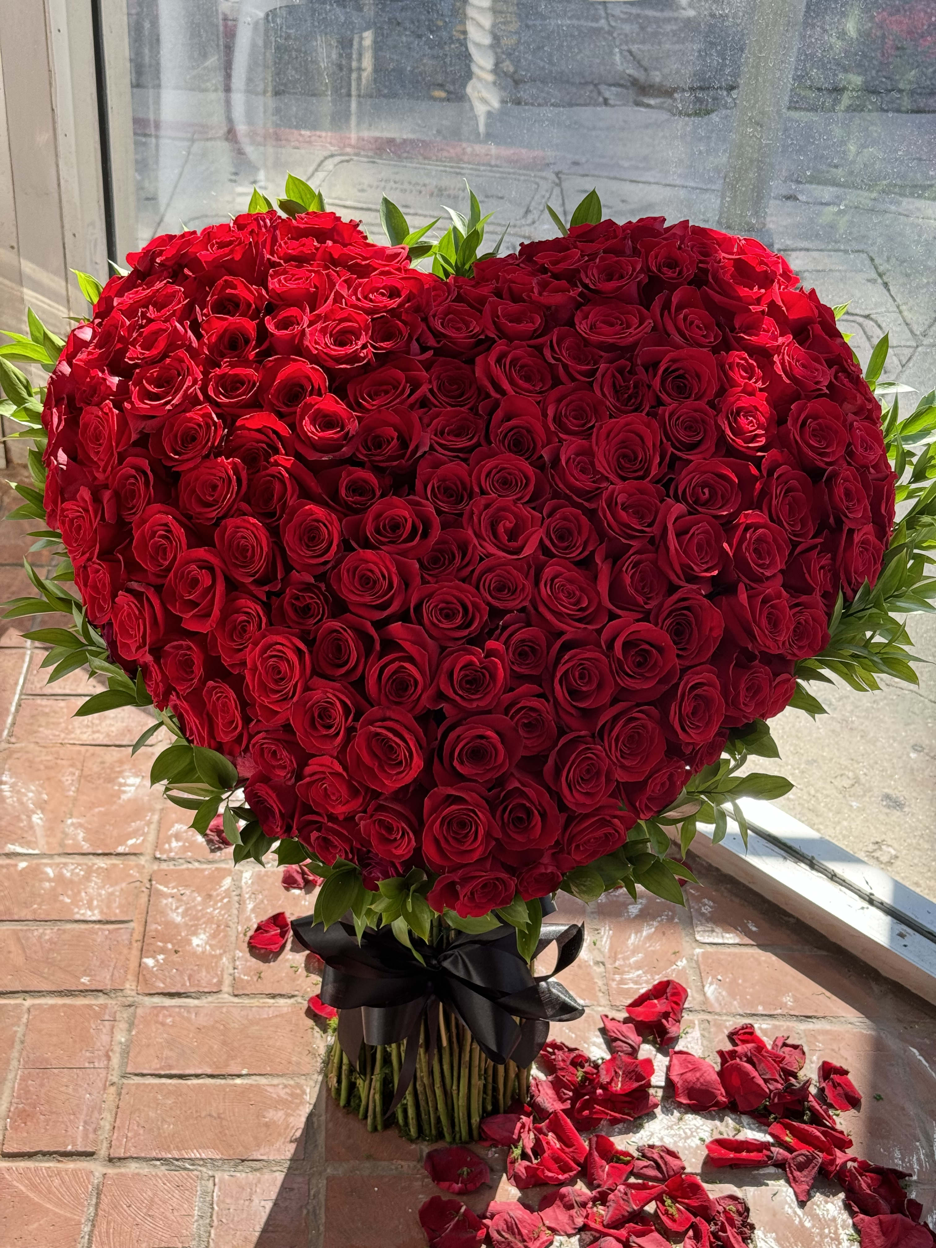 Heart-shaped bouquet of red roses tied with a black ribbon