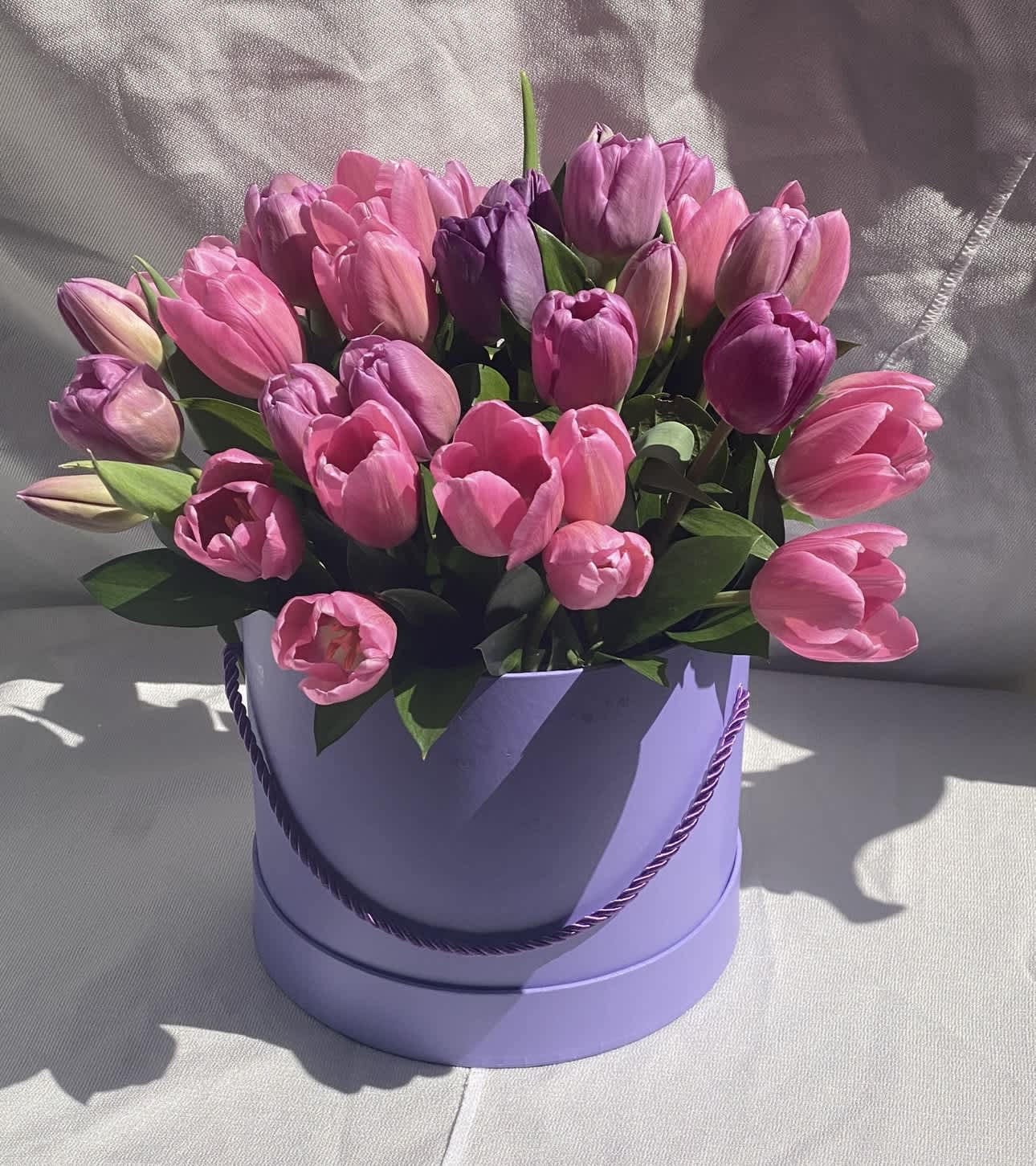 Pink and purple tulips arranged in a lavender round box