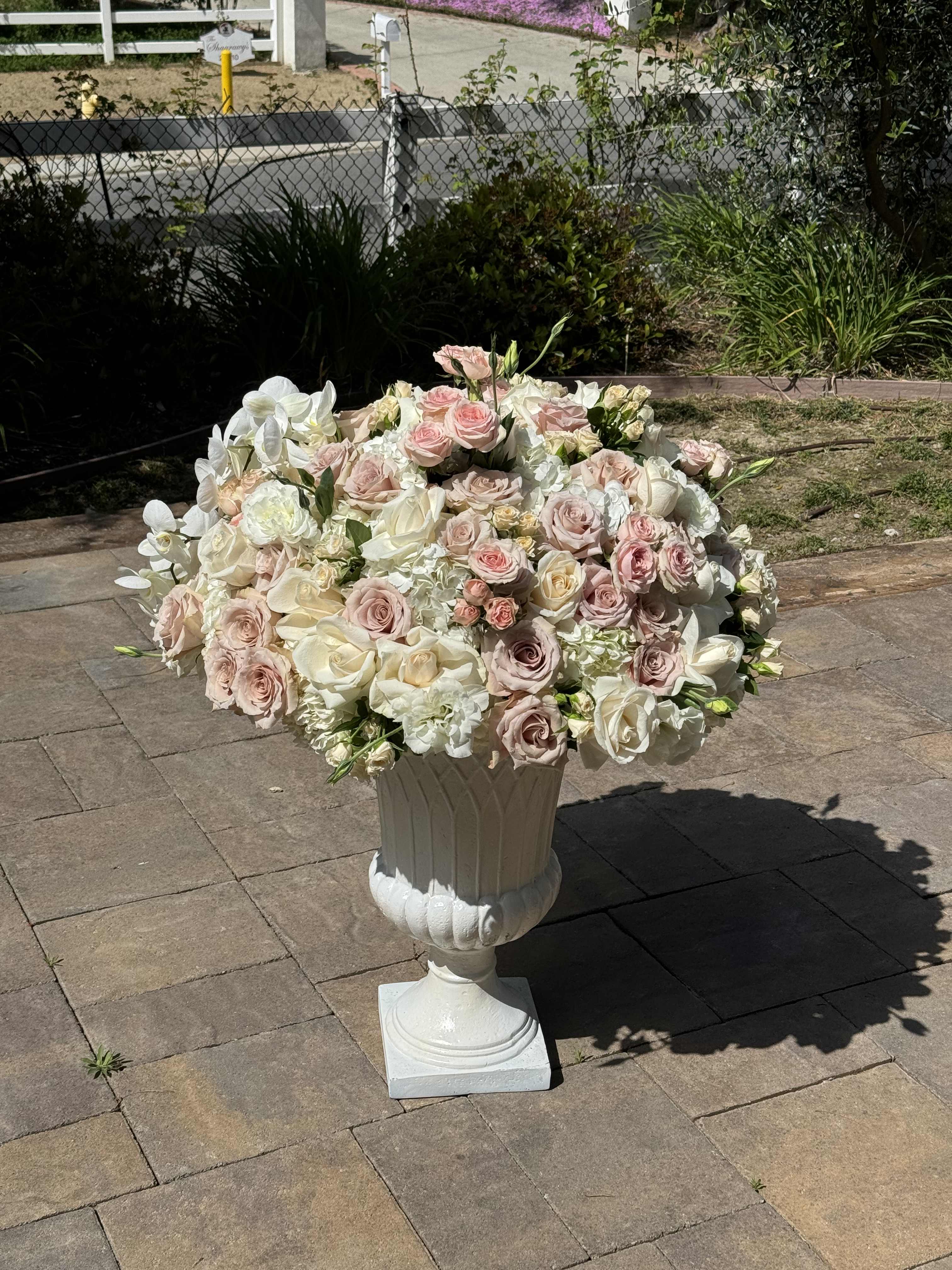 Large pastel rose arrangement in a white pedestal urn