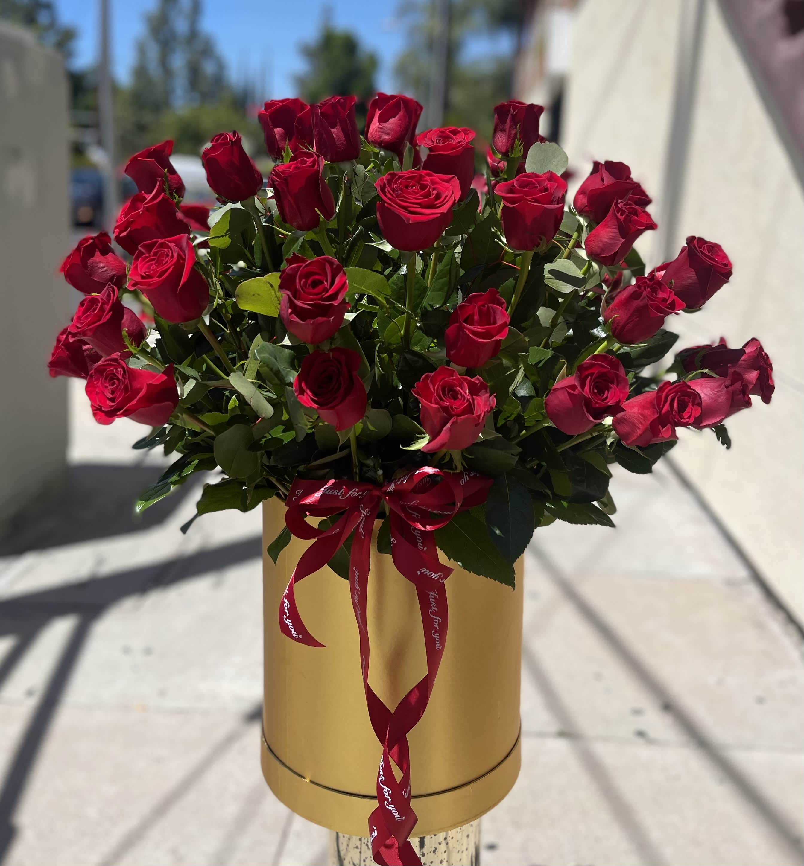 Bouquet of red roses in a gold hatbox with a red ribbon