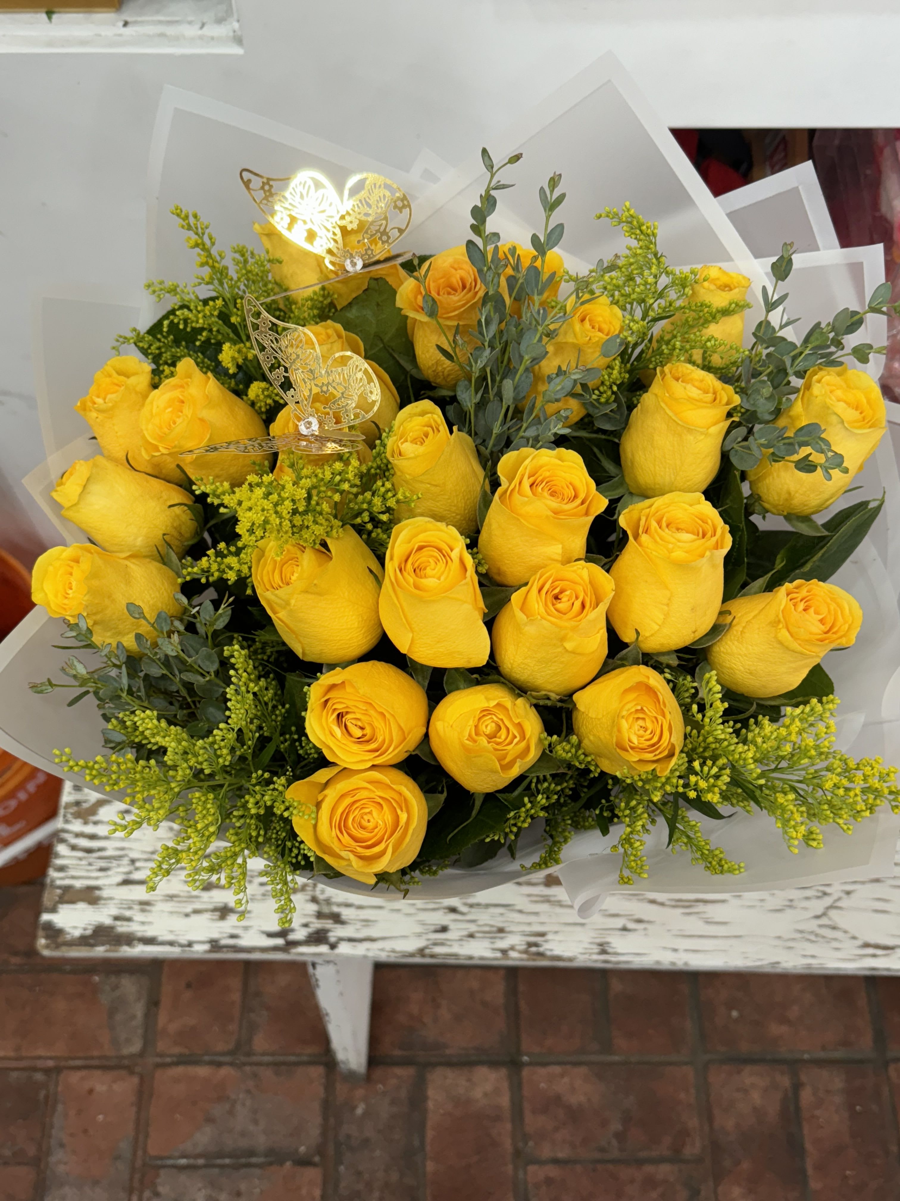 Bouquet of yellow roses with greenery and butterfly picks