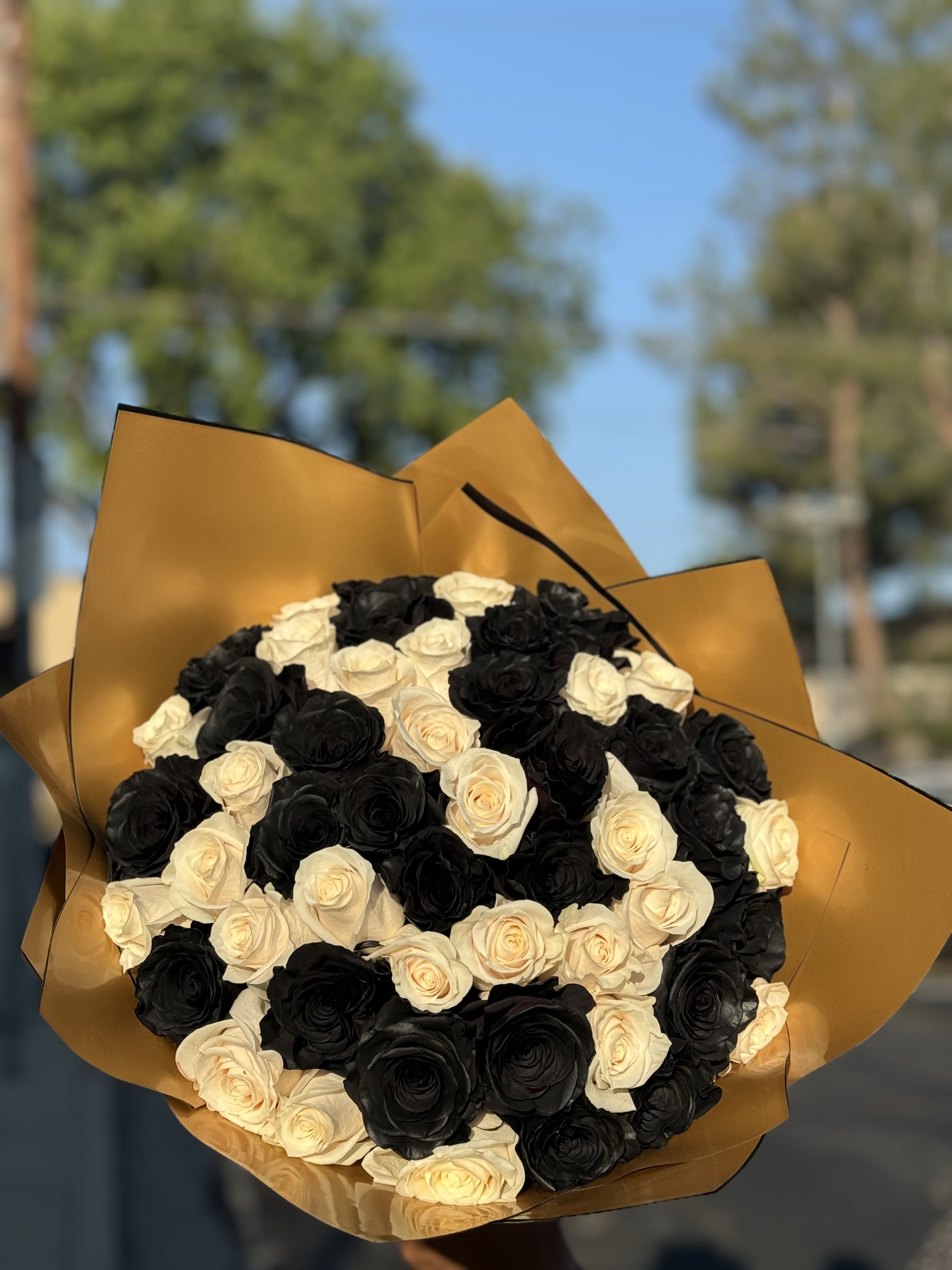 Bouquet of black and cream roses wrapped in gold paper