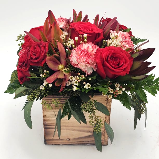 Red roses and pink carnations in a wooden box arrangement
