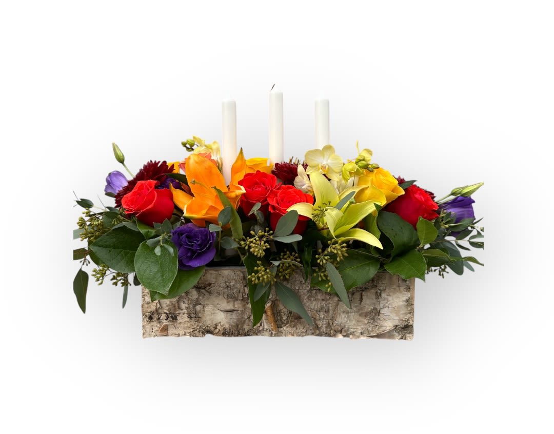 Colorful floral centerpiece with three white candles in a birch bark container