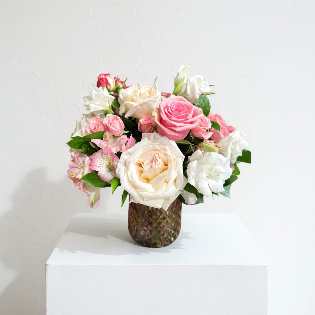 Pink and white rose bouquet in a textured glass vase