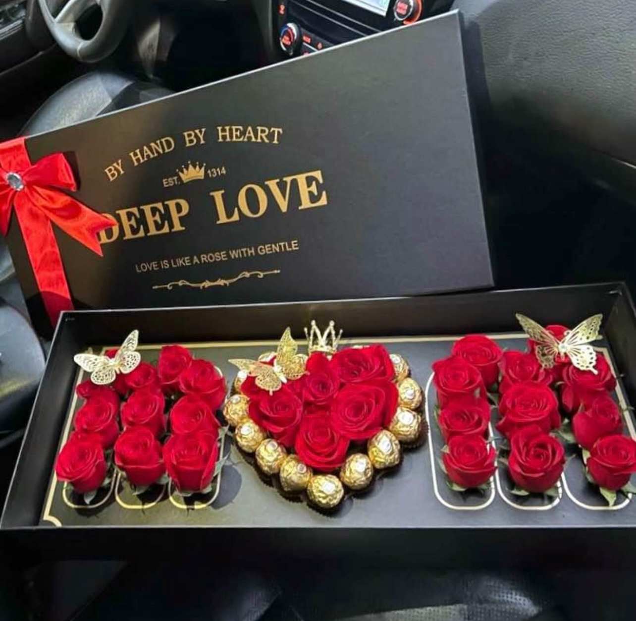 Black gift box with red roses and chocolates arranged inside