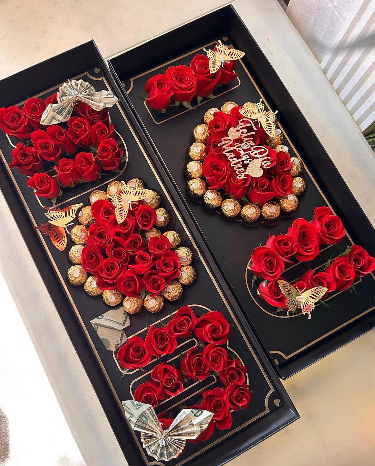 Black gift boxes with red roses, chocolates, and folded cash bows