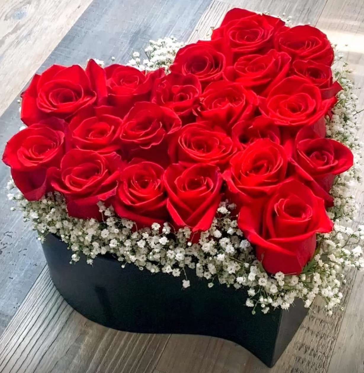 Heart-shaped box filled with red roses and white baby's breath