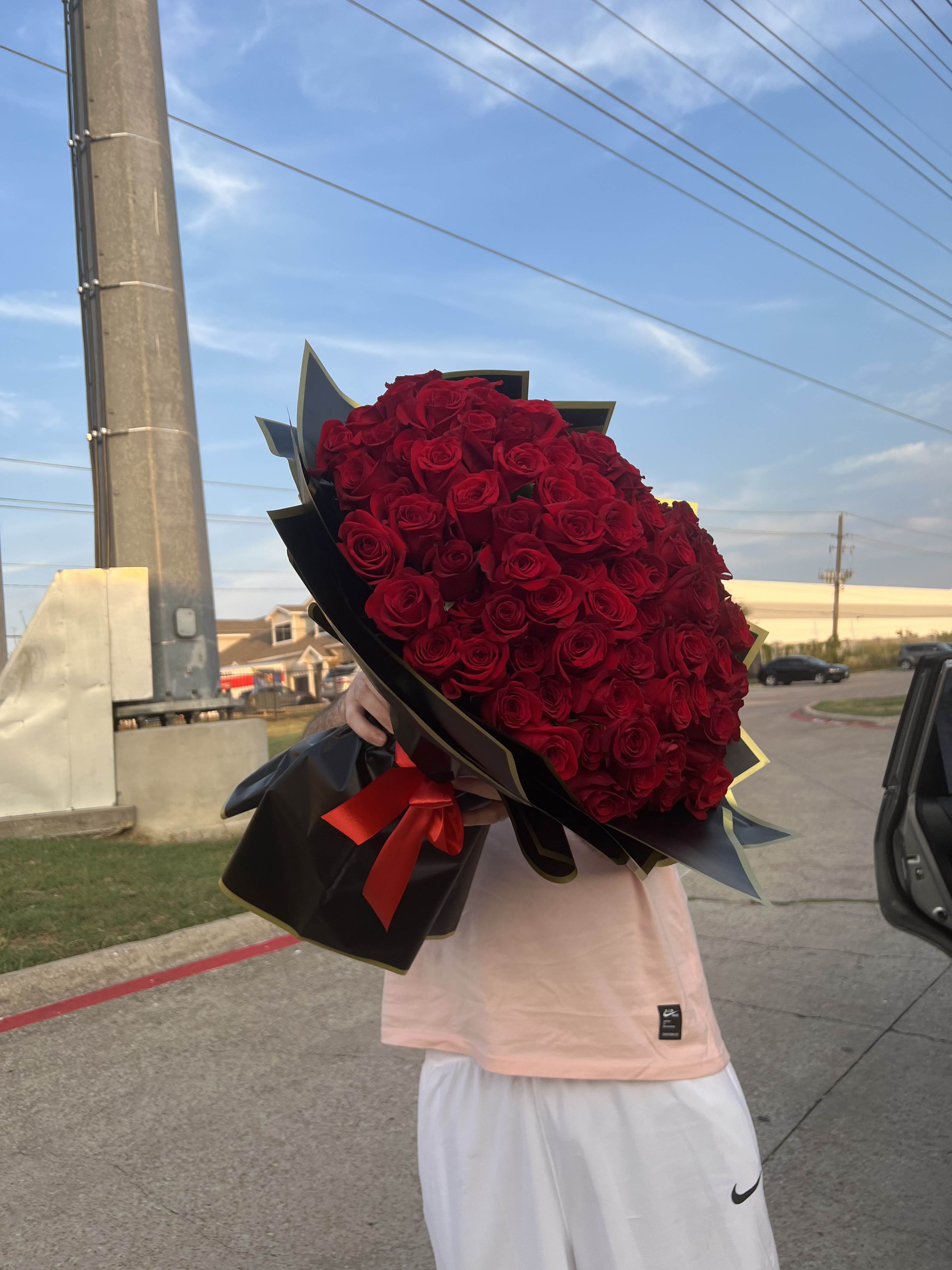 Large bouquet of red roses wrapped in black paper with a red ribbon
