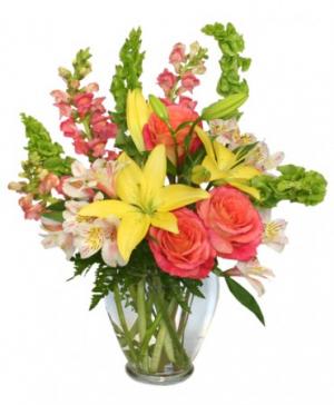Bouquet of yellow lilies, pink roses, and snapdragons in a glass vase