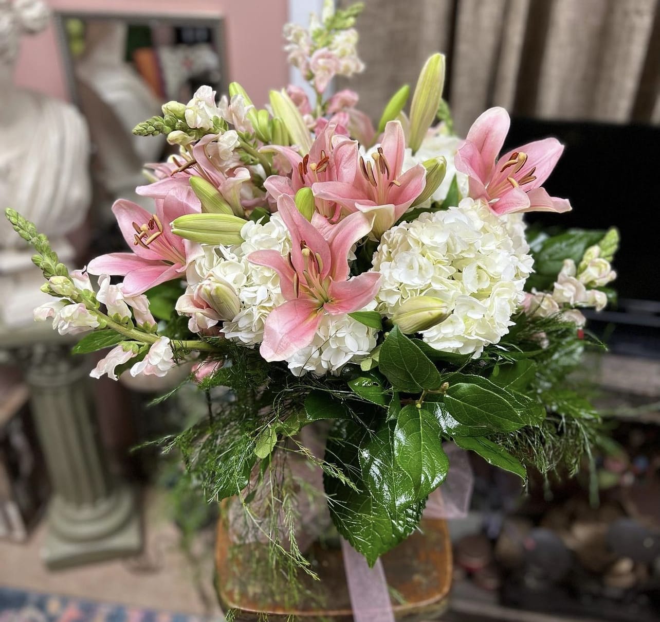 Pink lilies and white hydrangeas arranged in a glass vase