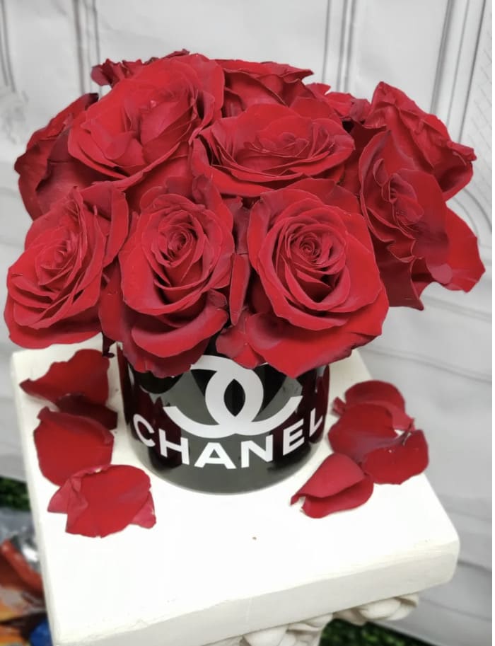 Red roses arranged in a black Chanel box with scattered petals