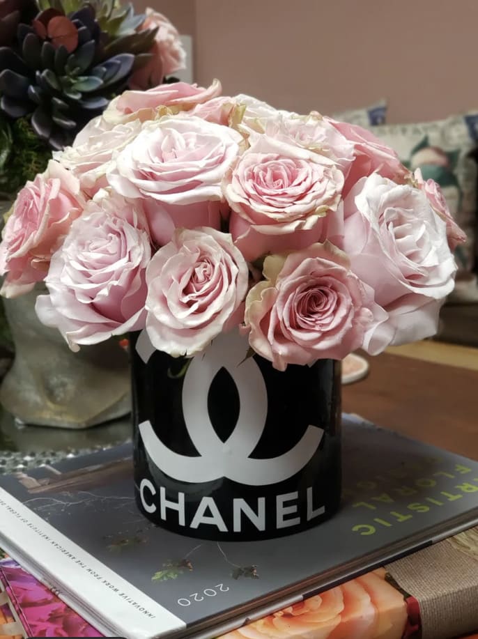 Pink roses arranged in a black Chanel container
