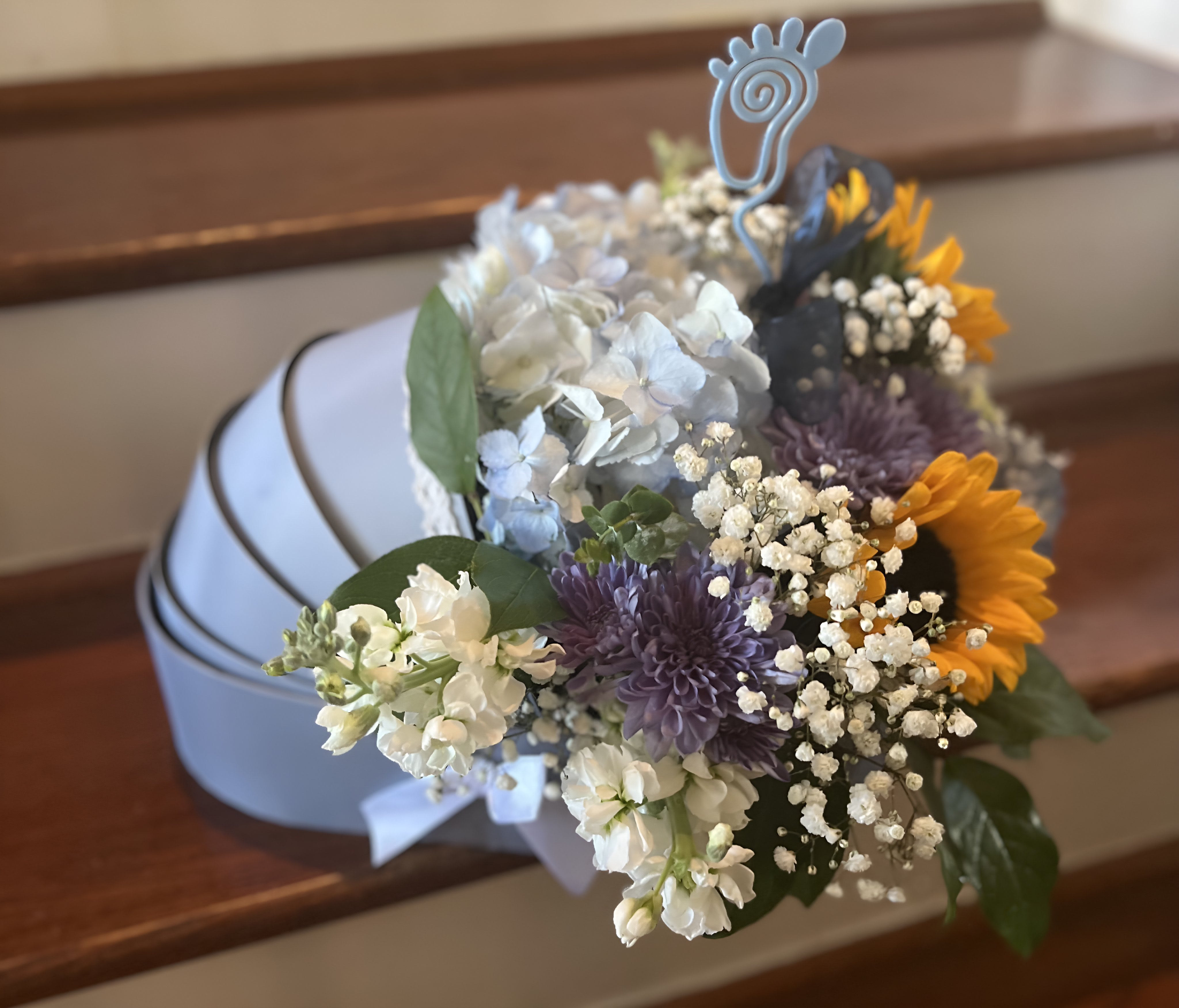 Bouquet of white, purple, and yellow flowers in a light blue hatbox