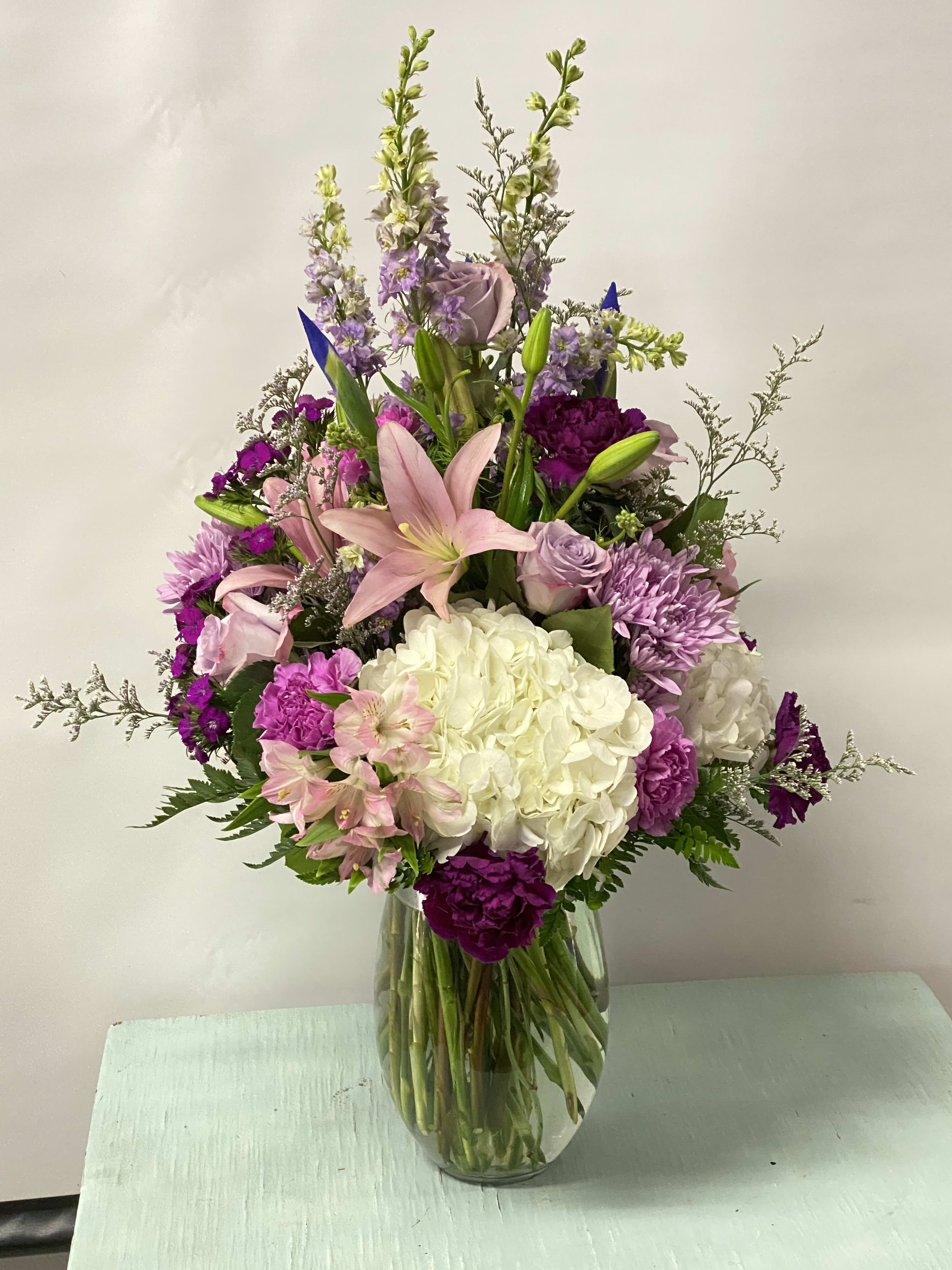 Mixed bouquet of pink, purple, and white flowers in a glass vase