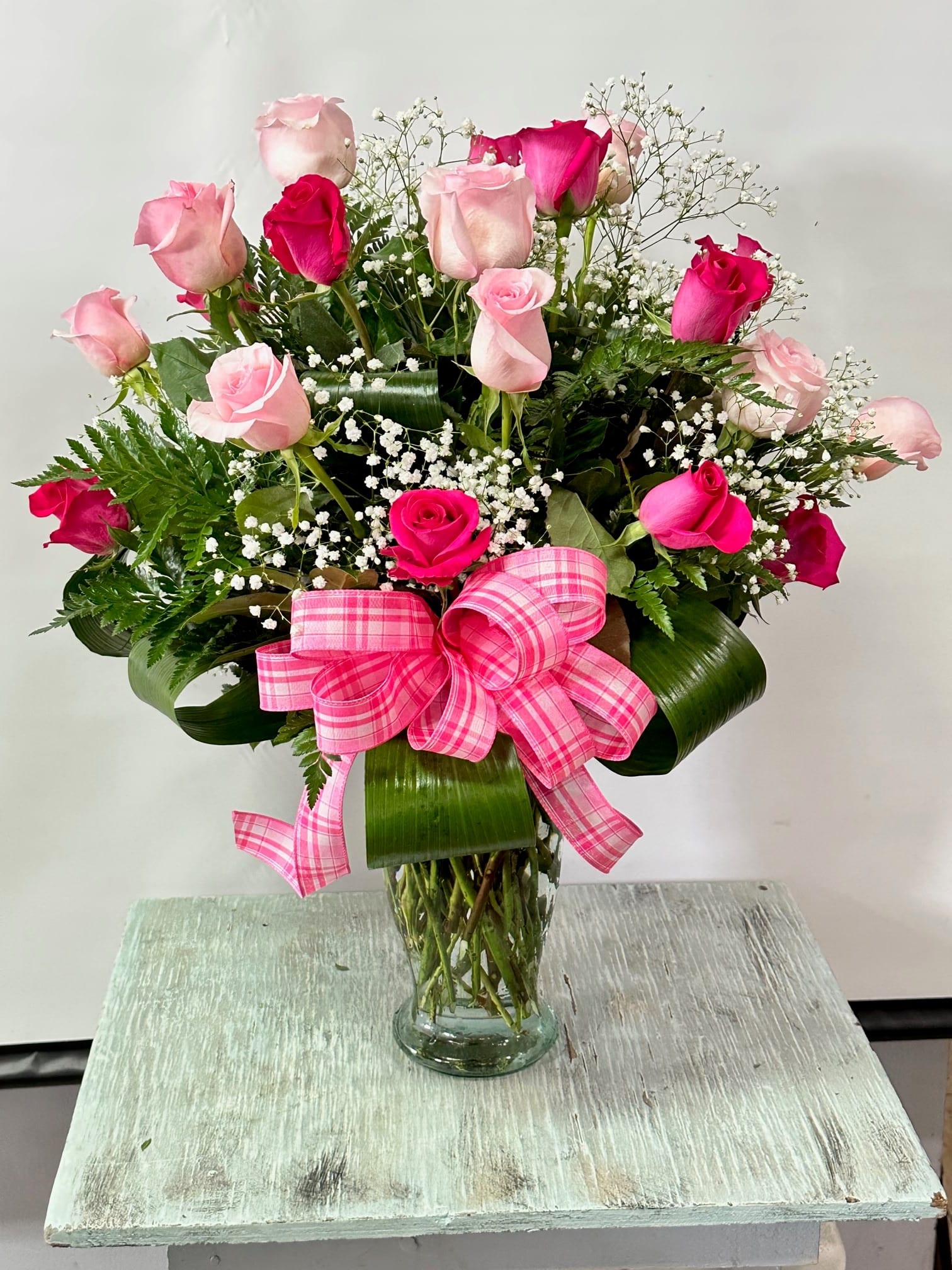 Pink and hot pink roses in a clear glass vase with a pink plaid bow