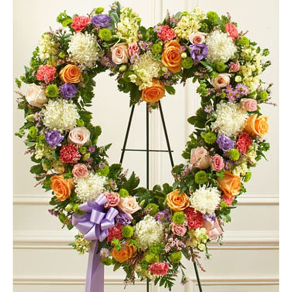 Heart-shaped floral wreath on an easel with a purple ribbon bow