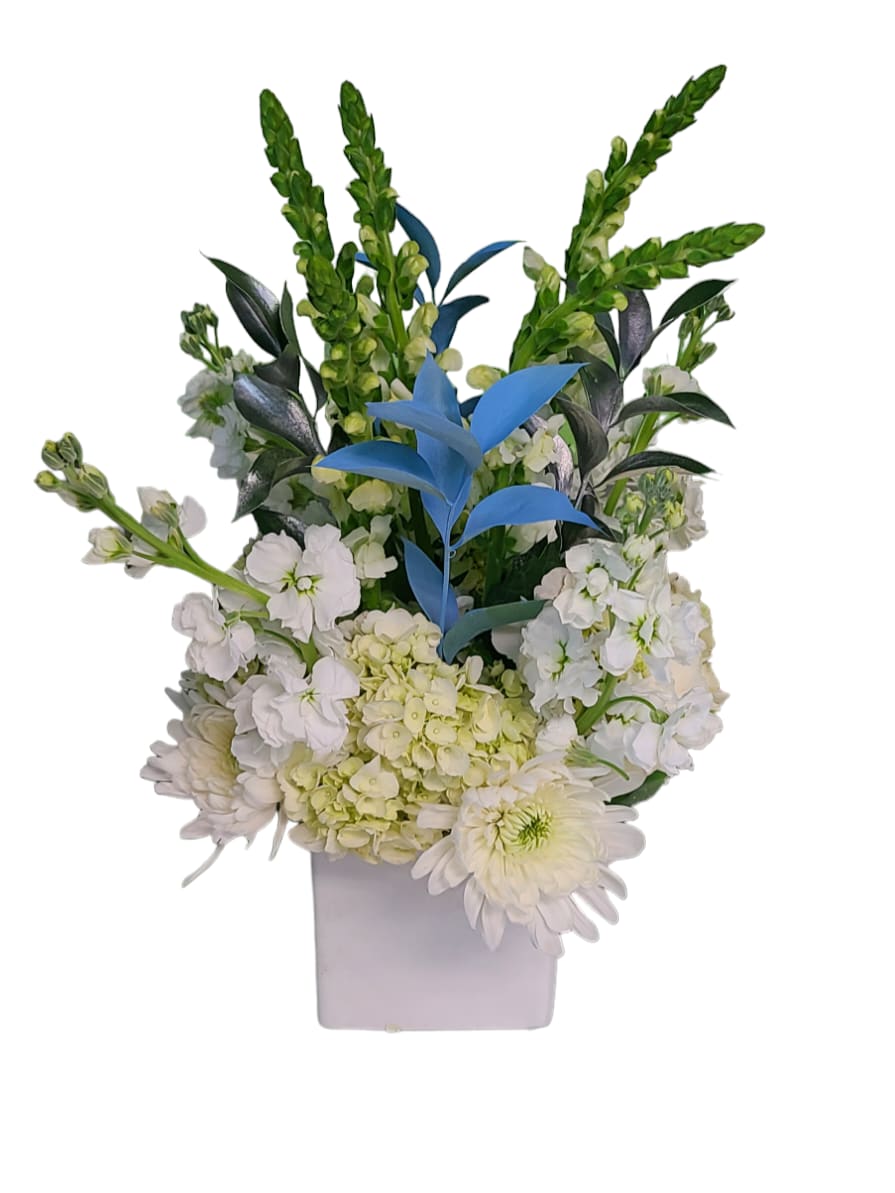 White floral arrangement in a square vase with blue accent leaves