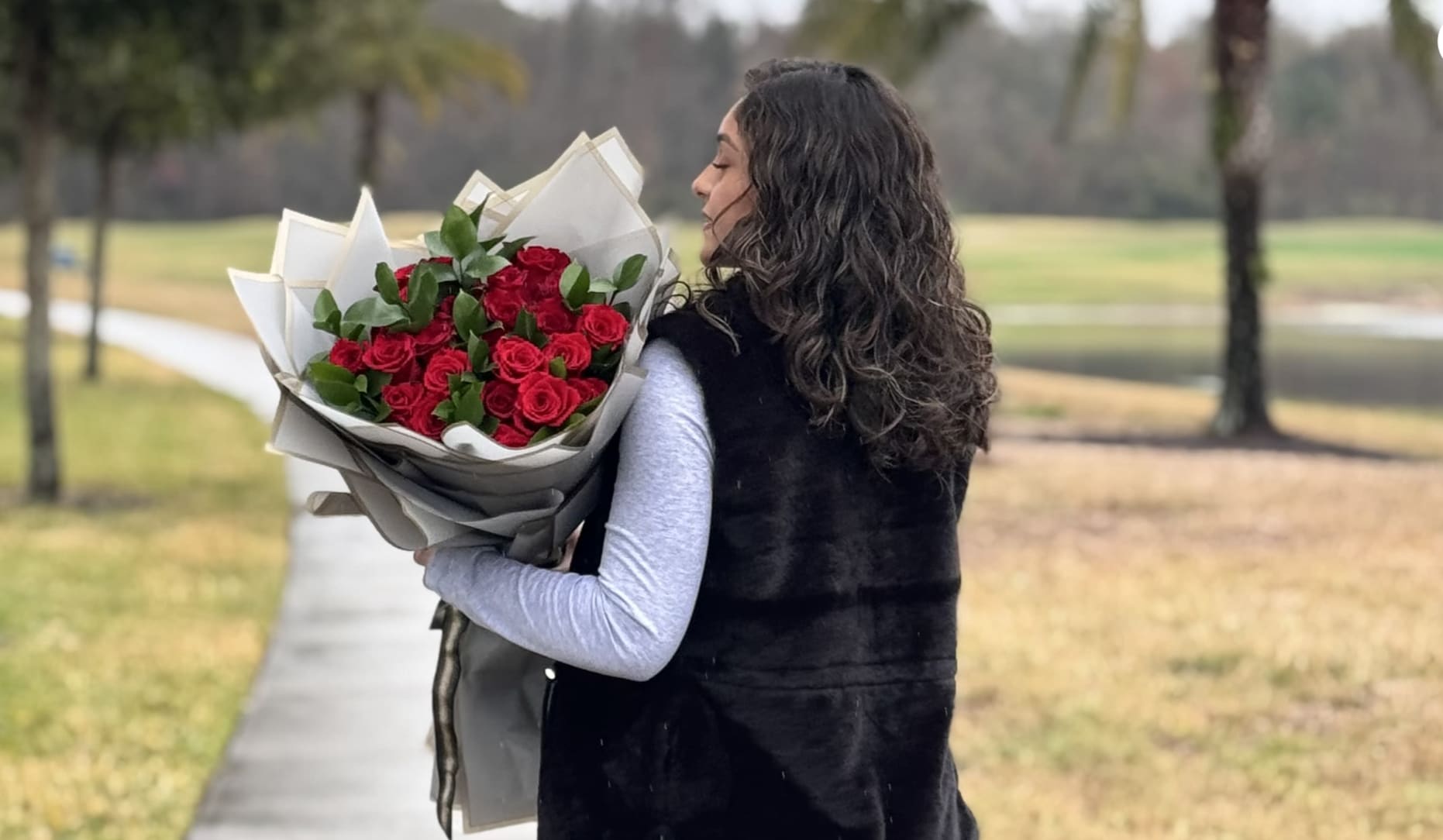 Woman holding a bouquet of red roses wrapped in paper