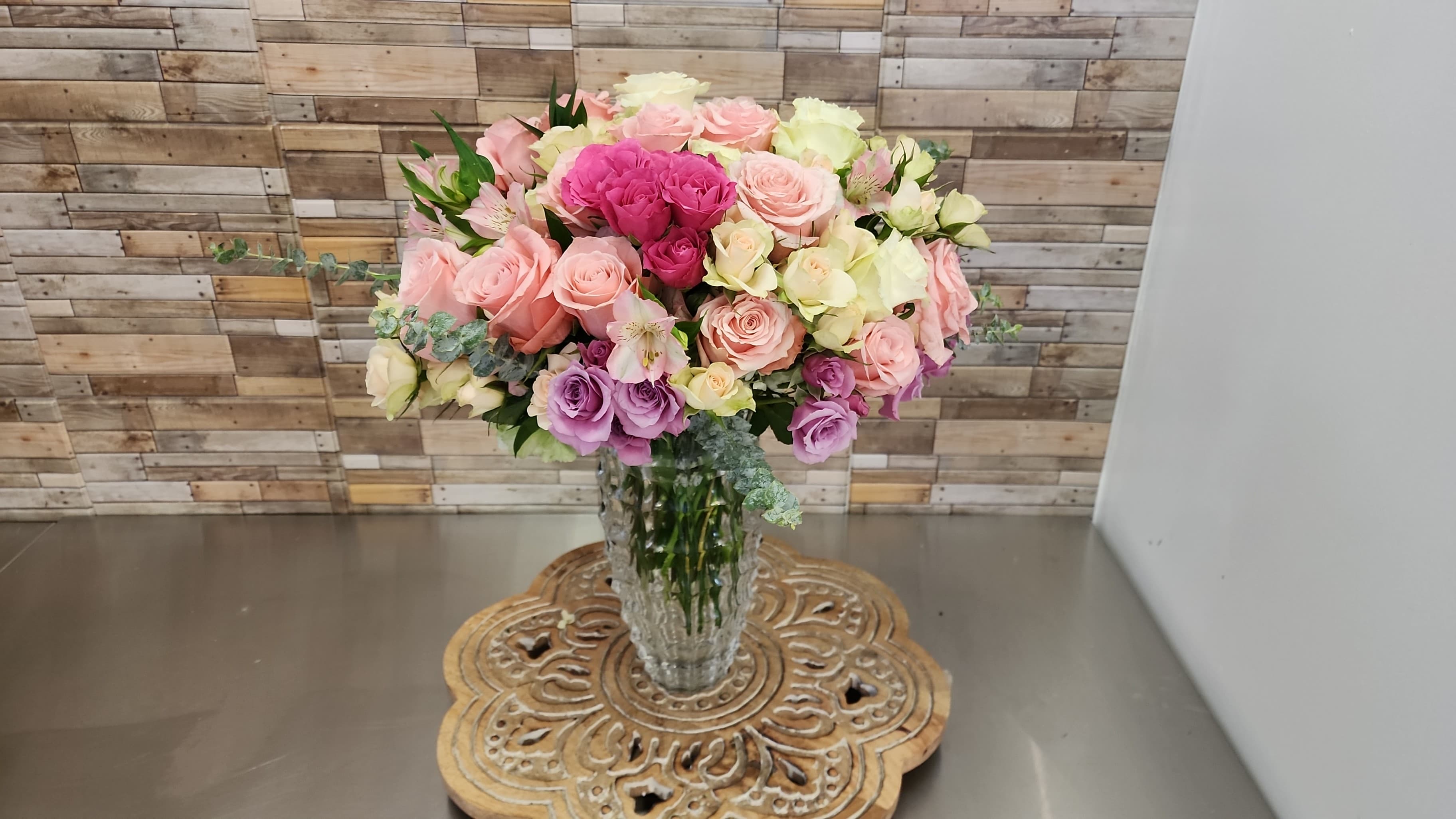 Bouquet of pink, cream, and lavender roses in a clear glass vase