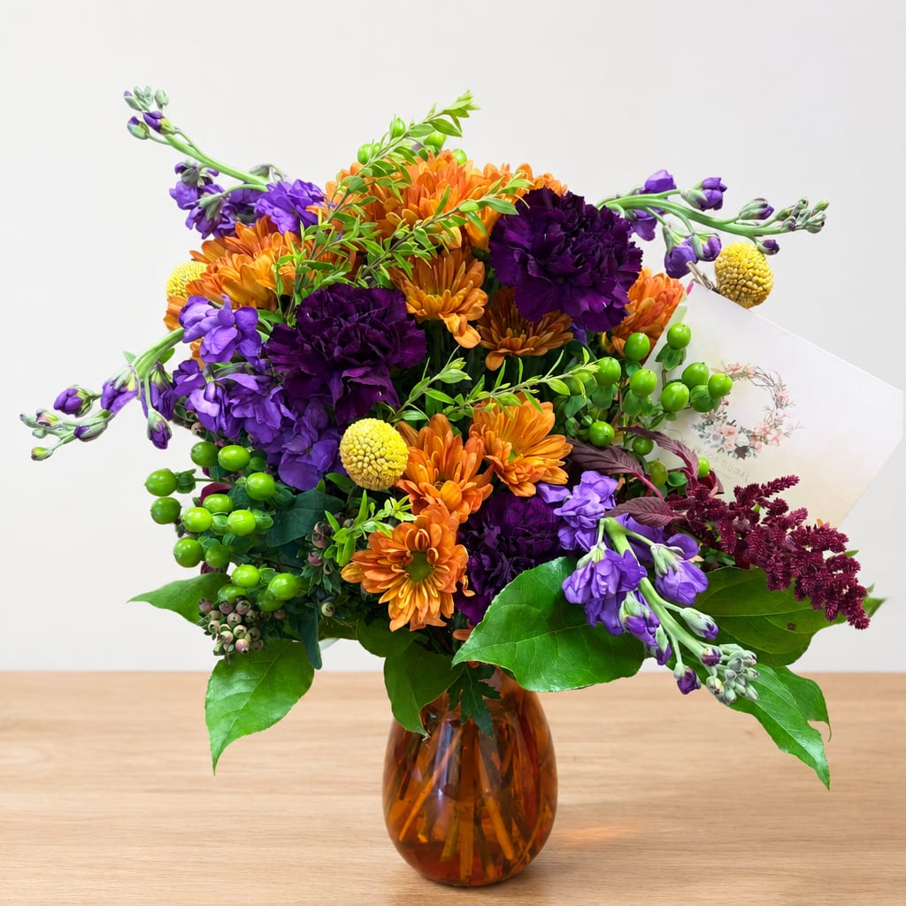 Orange and purple flowers in an amber glass vase