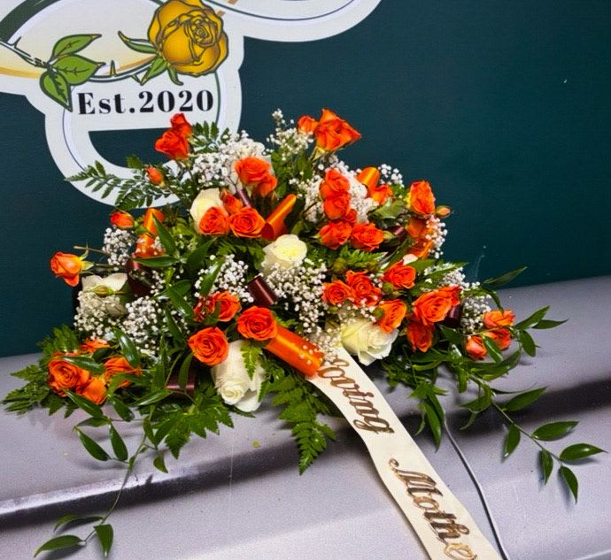 Orange and white rose arrangement with baby's breath on a casket