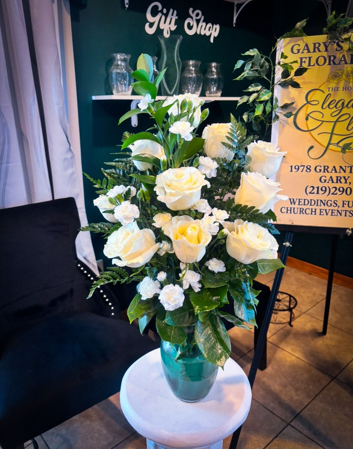 White roses and carnations in a teal glass vase