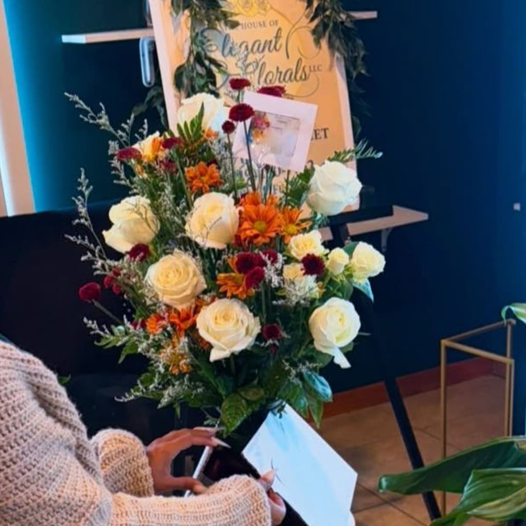 Bouquet of white roses and orange flowers being held by a person