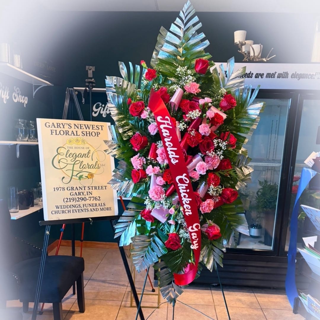 Large red and pink funeral spray on an easel with a ribbon