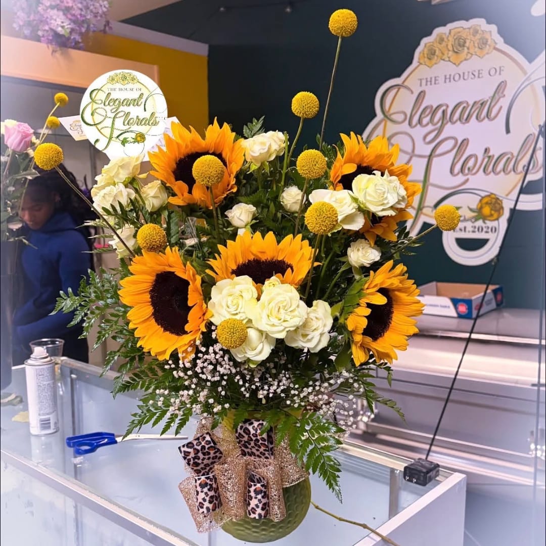 Sunflower and white rose arrangement in a green vase with leopard-print ribbon