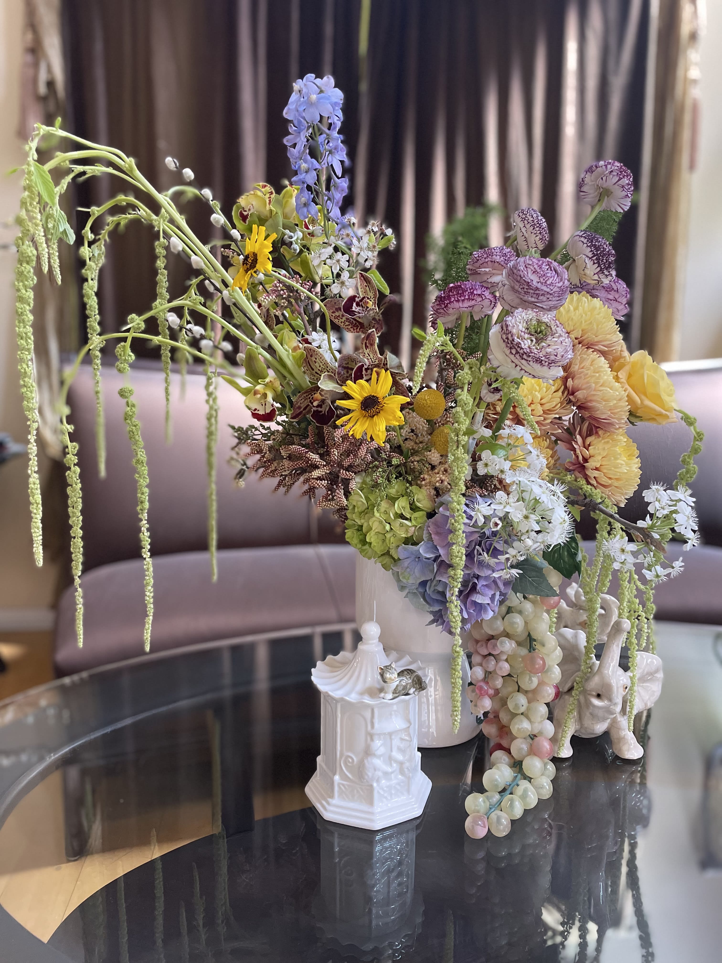 Large mixed floral arrangement in a white vase with cascading blooms