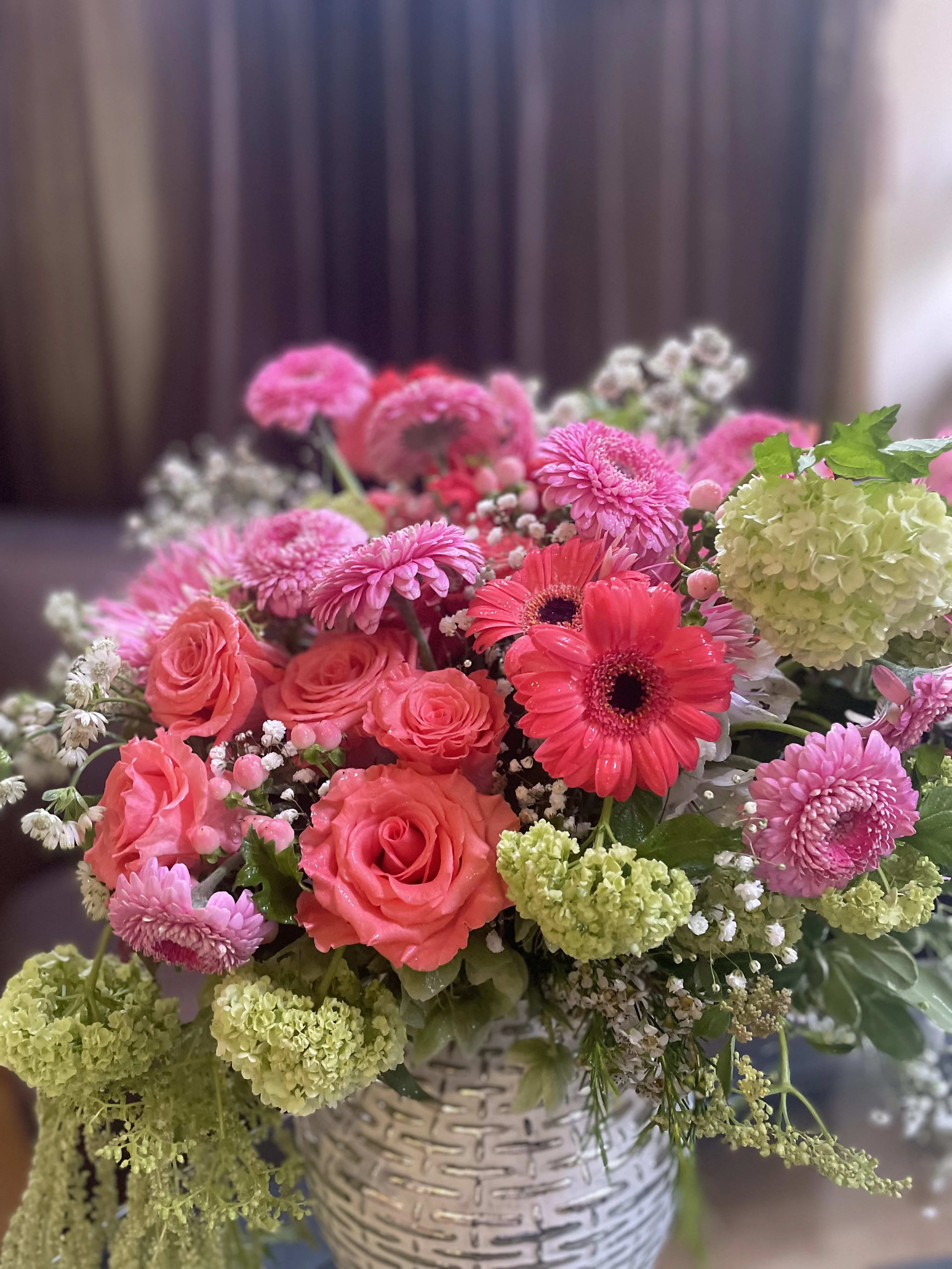 Pink and coral mixed bouquet in a white basket vase
