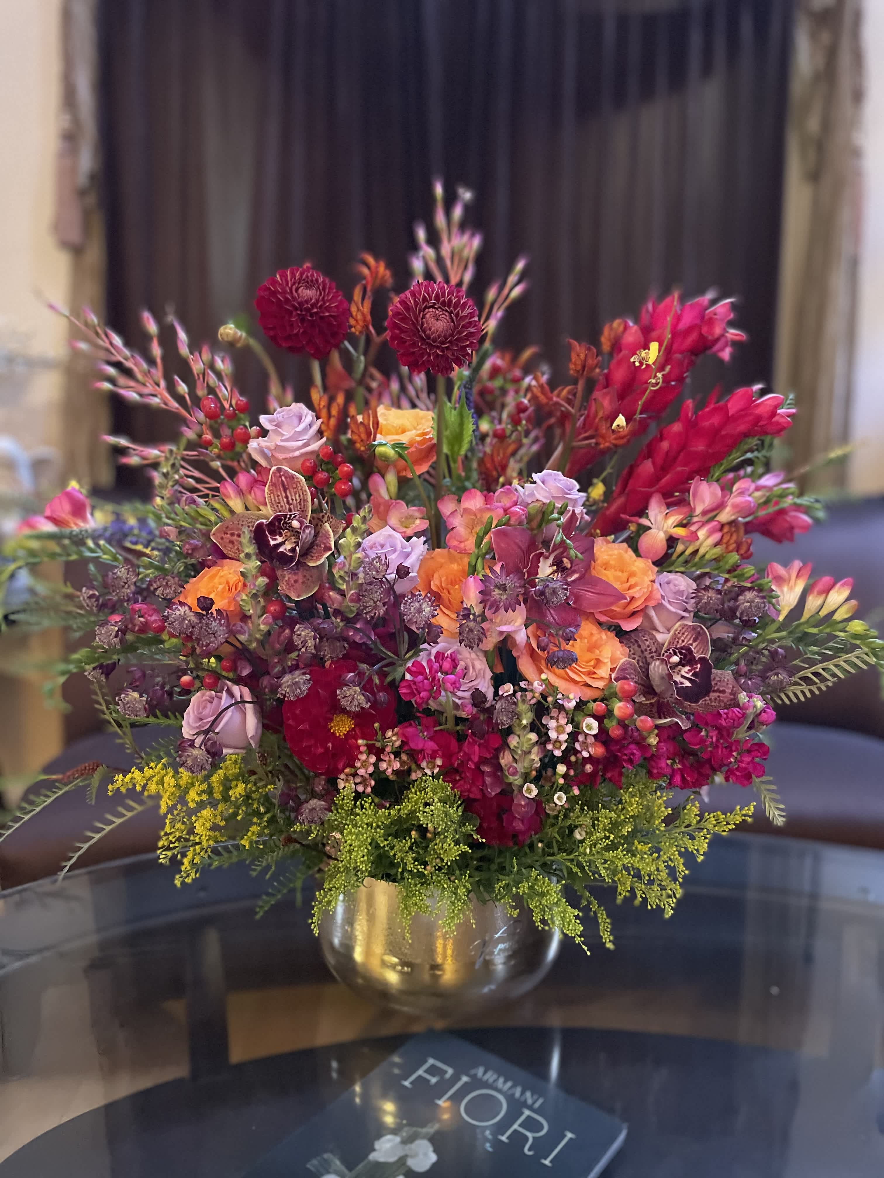 Colorful mixed bouquet in a gold vase with pink, orange, and burgundy blooms